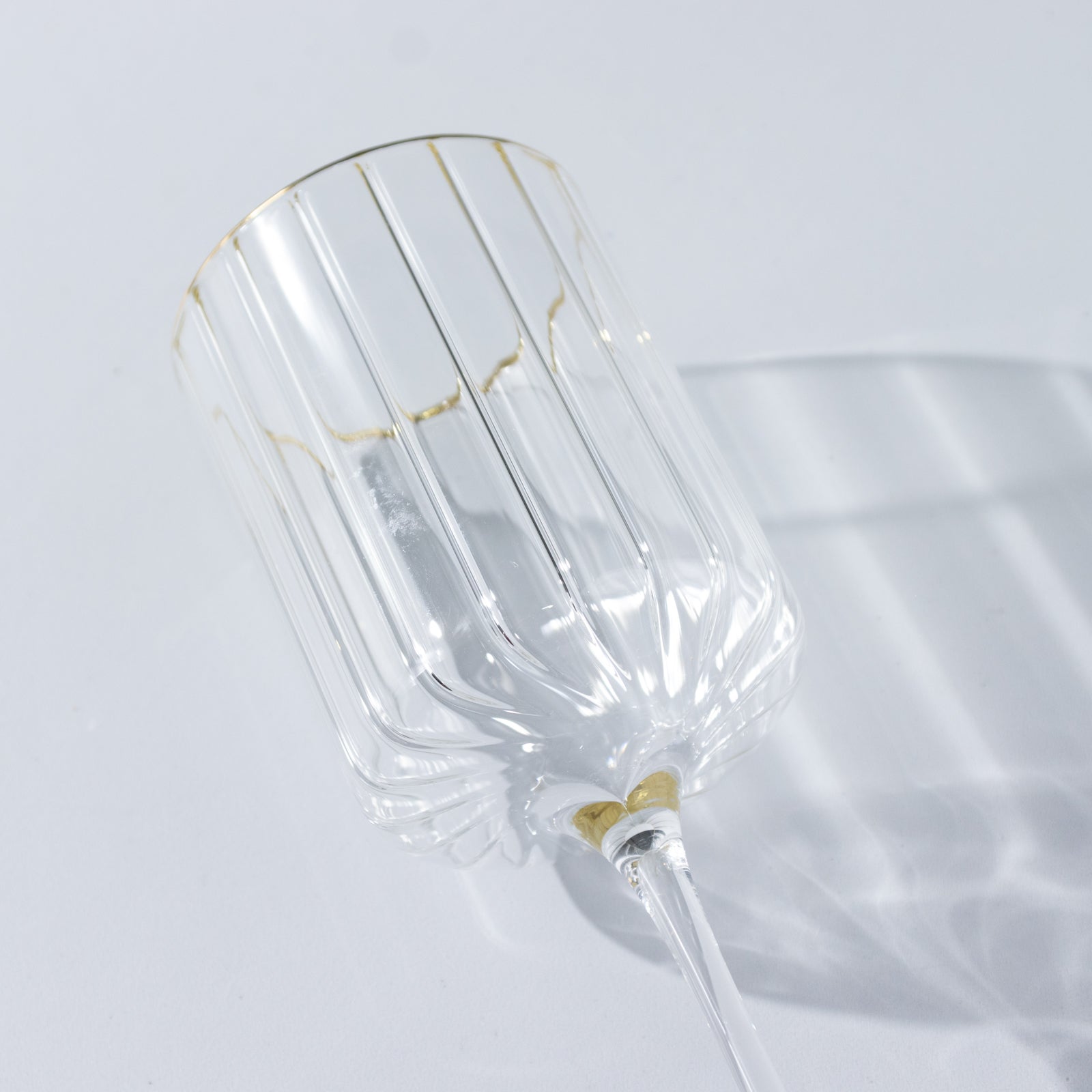 Clear glass vintage wine goblet with gold rim, ribbed design.