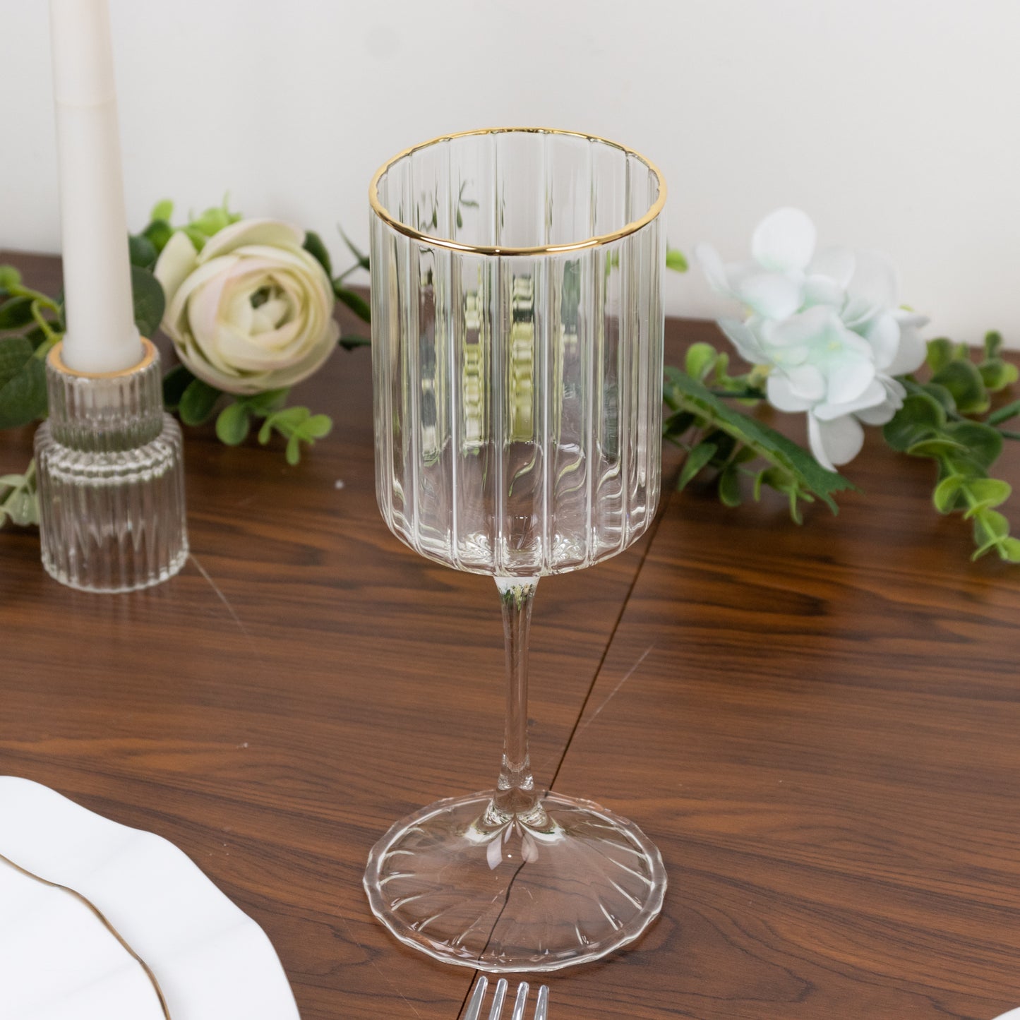 Clear ribbed glass goblet with gold rim on a wooden table.