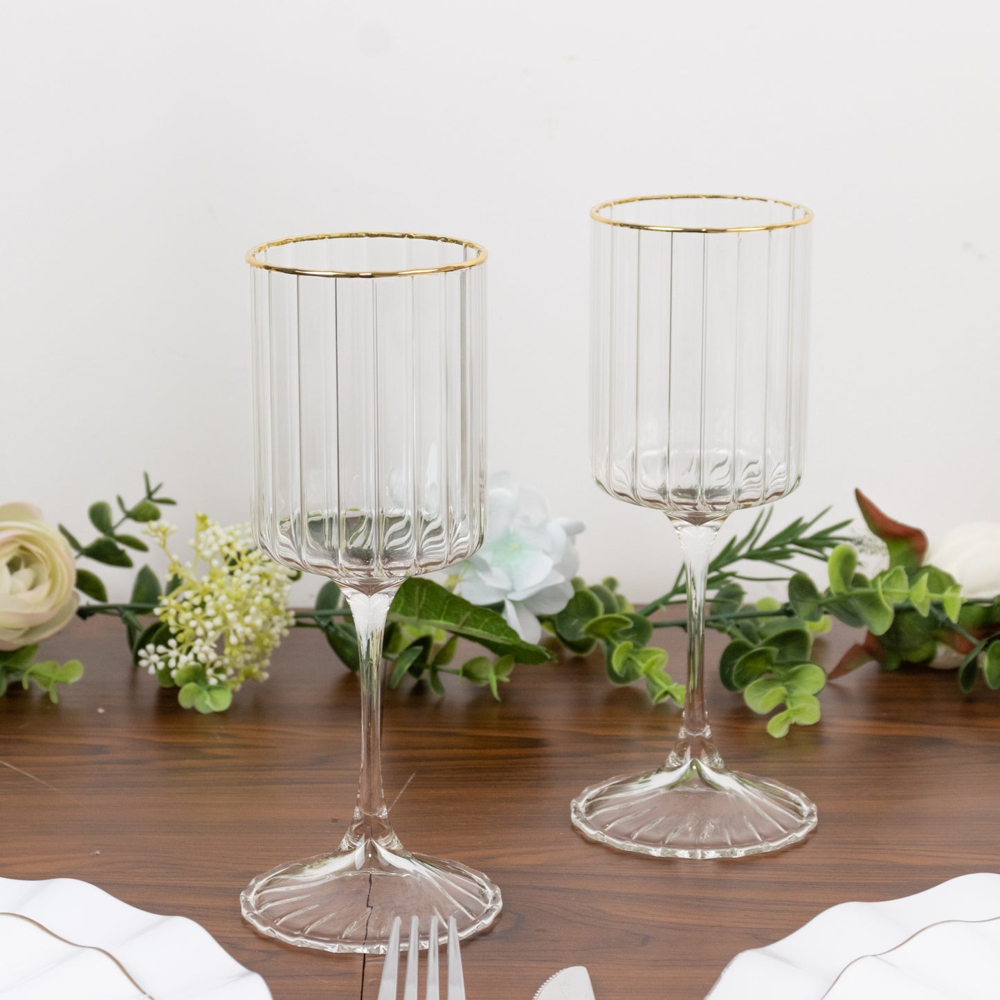 Clear ribbed wine goblet glasses with gold rim, classic drinkware for cocktails.