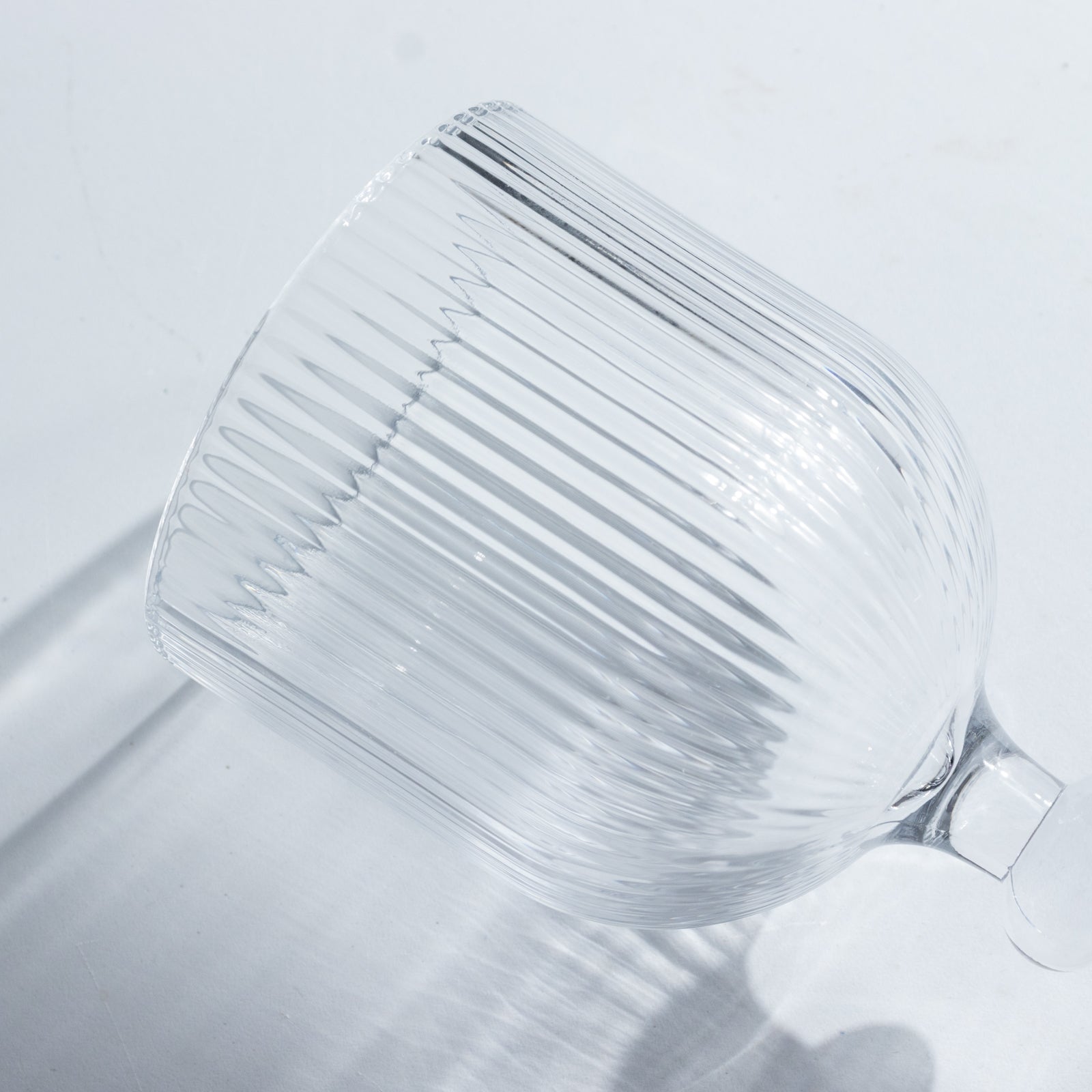 Clear ribbed wine glass with ball stem accent.
