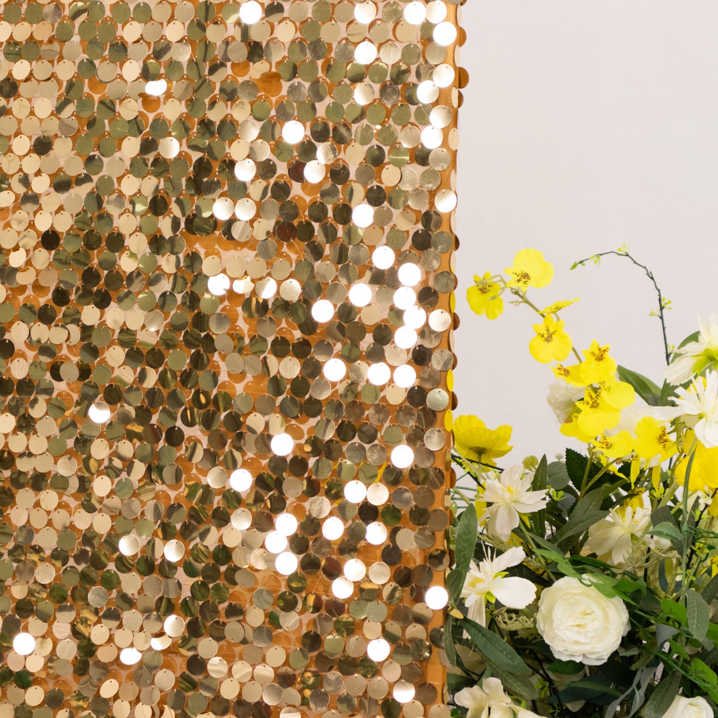 Gold sequin wedding arch cover with floral arrangement.