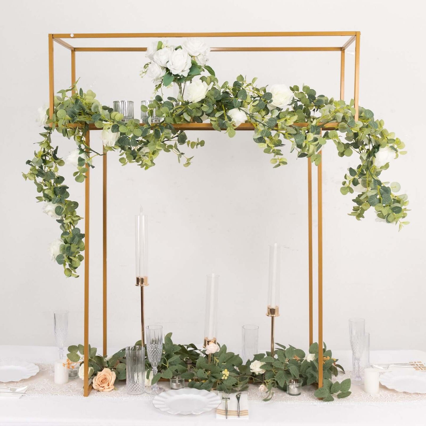 Gold floral arrangement tabletop display rack with greenery and white flowers.