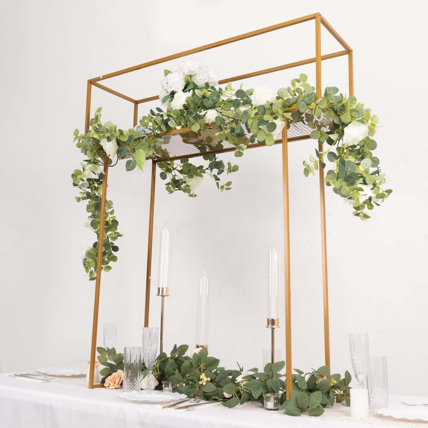 Gold floral arrangement tabletop display rack with greenery and candles.
