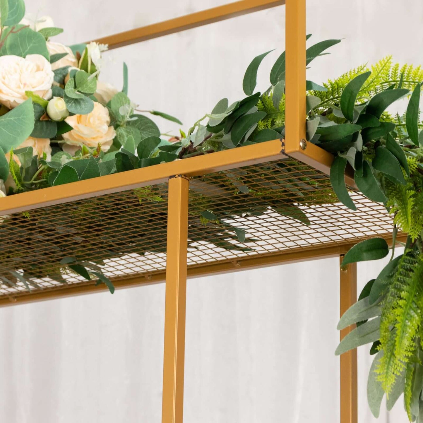 Gold floral arrangement tabletop display rack with greenery and flowers.