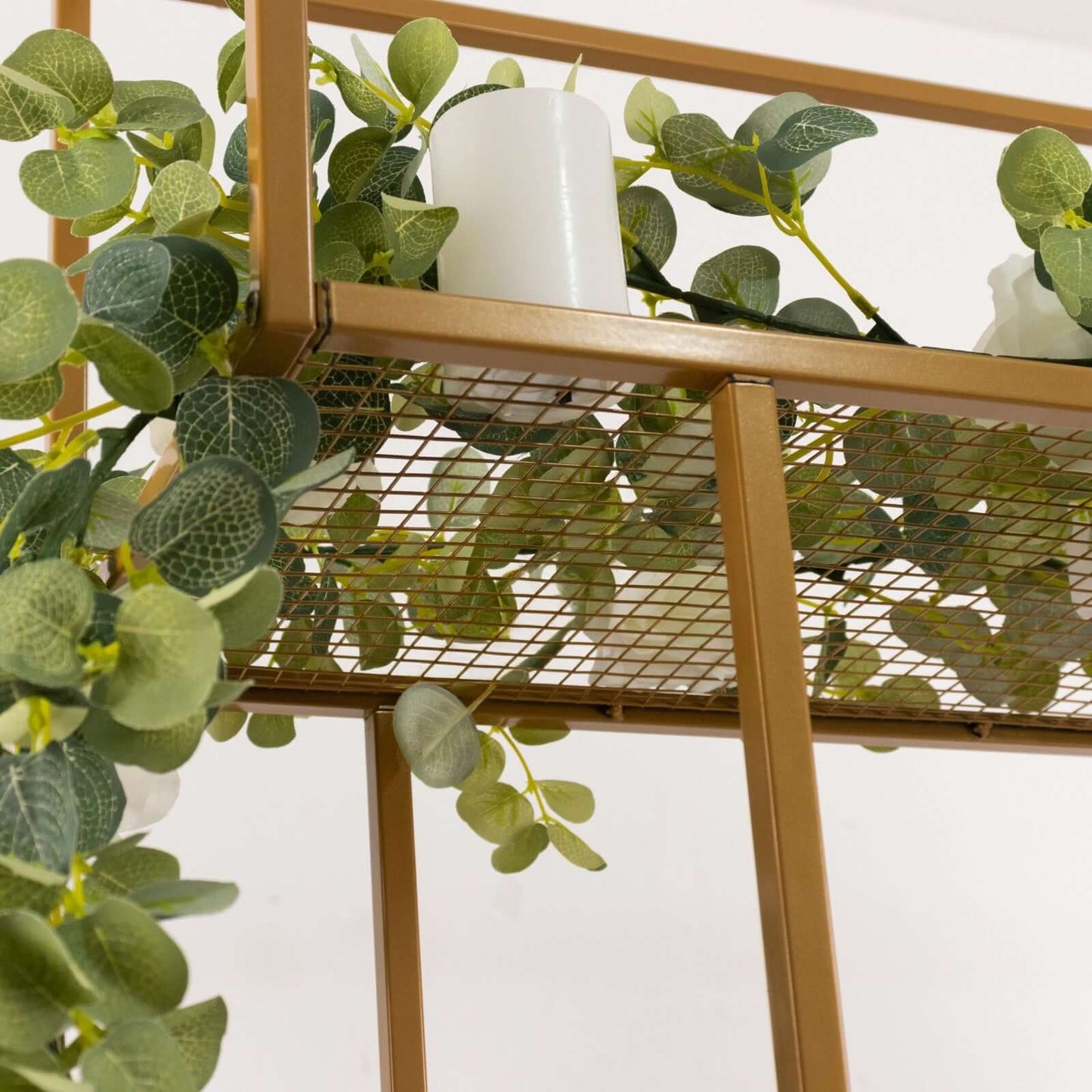 Gold metal floral arrangement tabletop display rack with greenery.