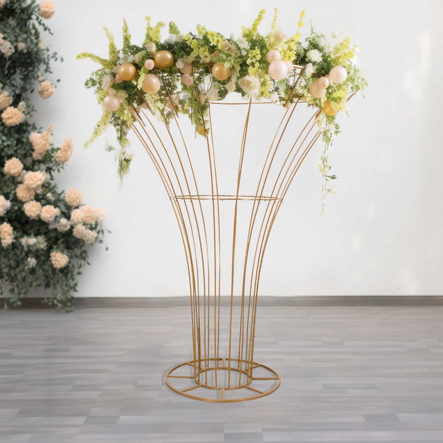 Gold metal floral display stand with greenery and decorative flowers.