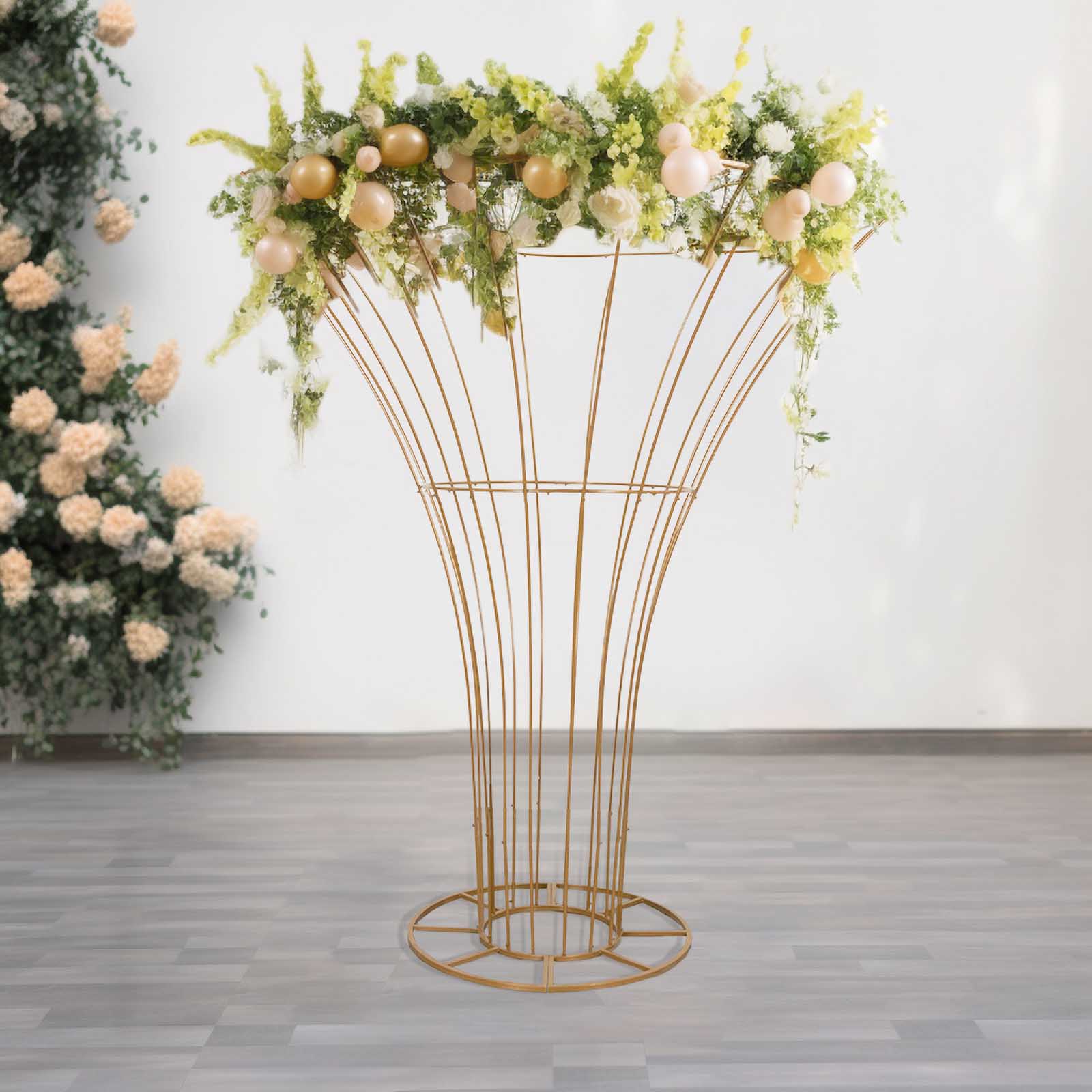 Gold metal floral display stand with greenery and decorative flowers.