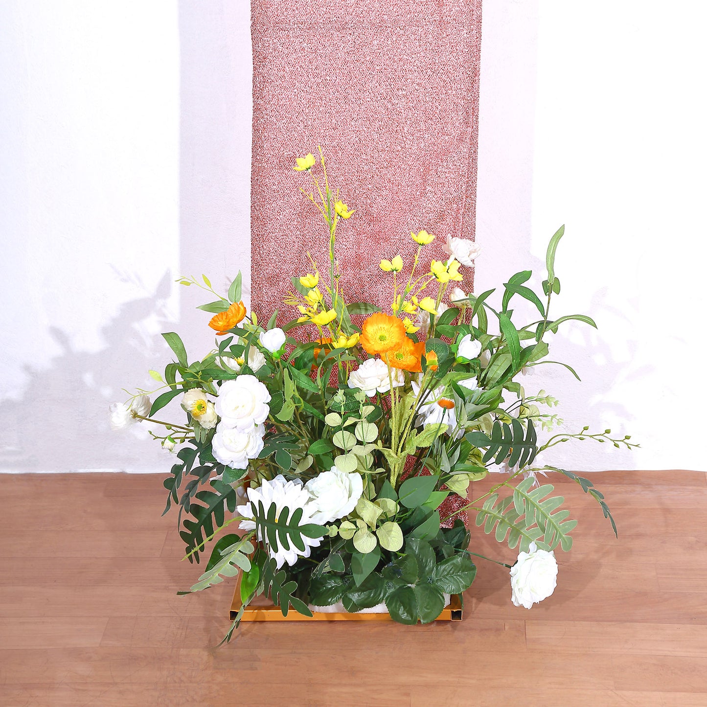 Rose gold shimmer tinsel backdrop with floral arrangement at base.