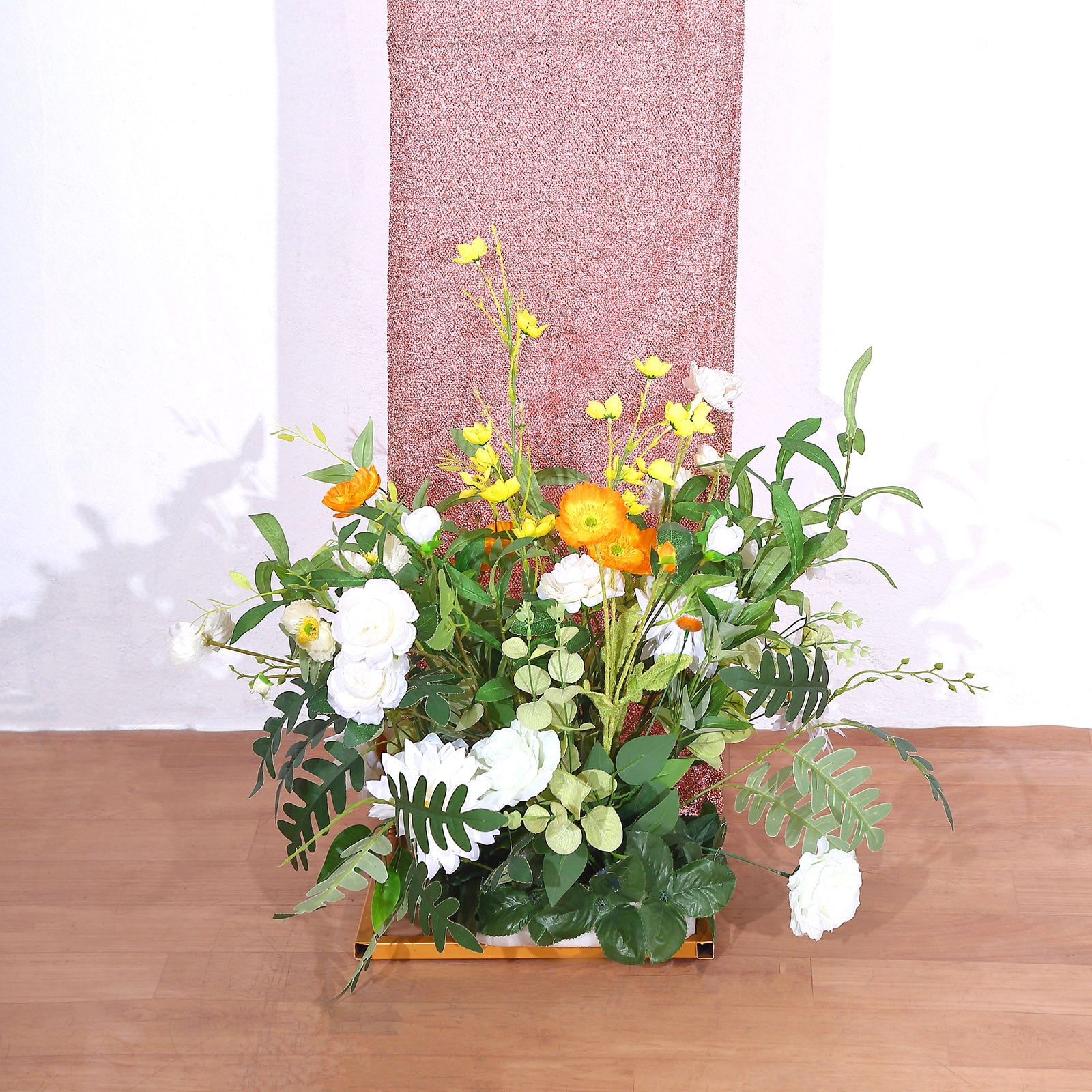 Rose gold shimmer tinsel backdrop with floral arrangement at base.
