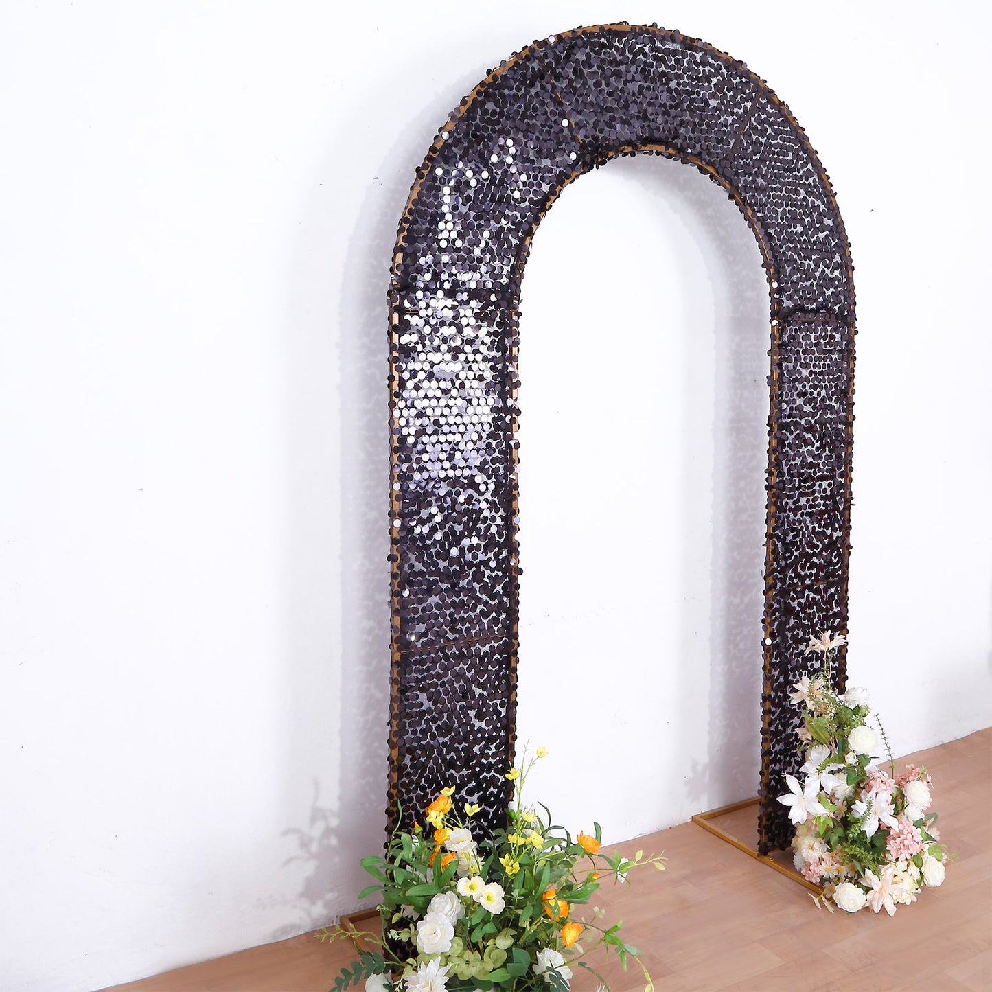 Black double-sided sequin wedding arch backdrop with floral arrangements.