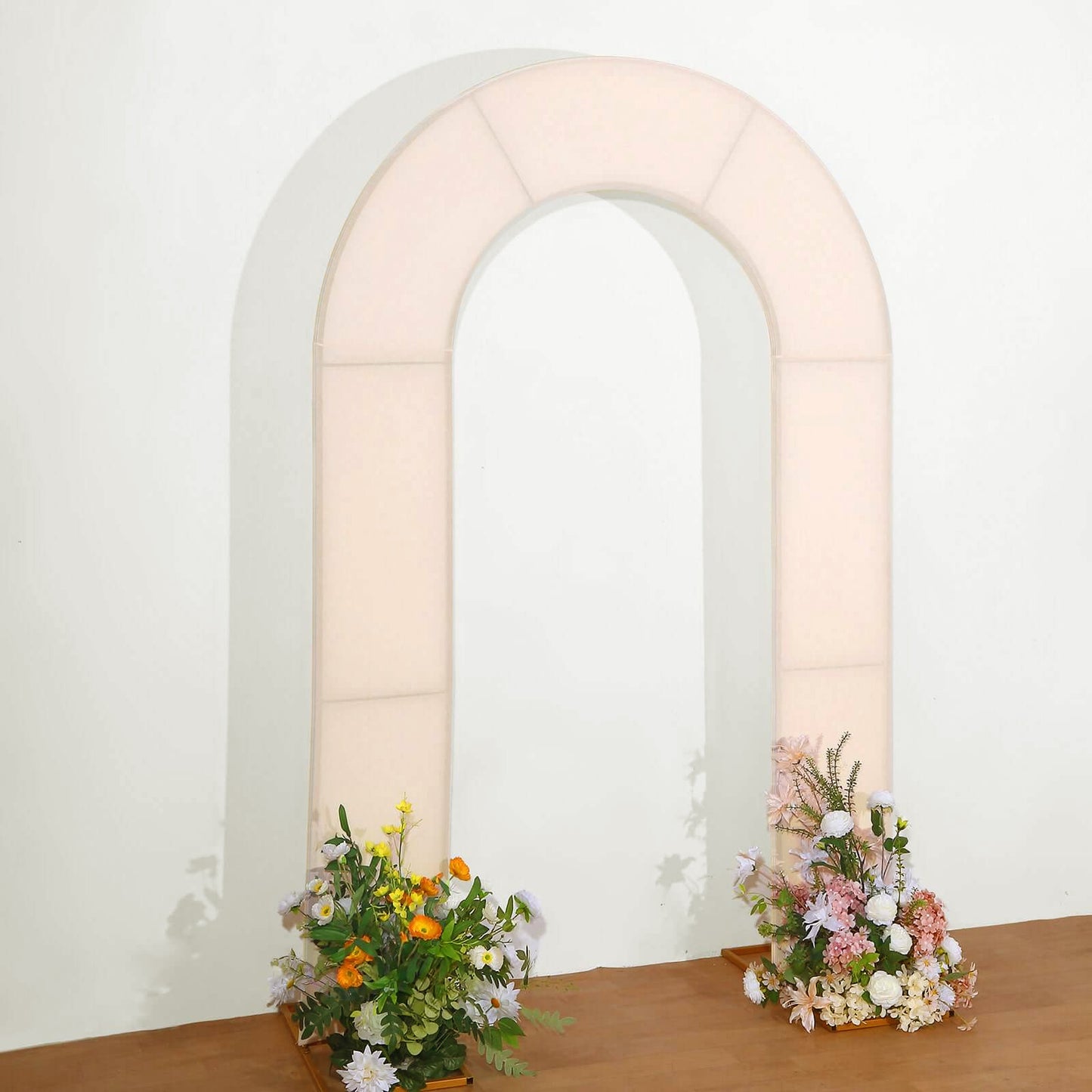 Blush spandex fitted wedding arch cover with floral arrangements.