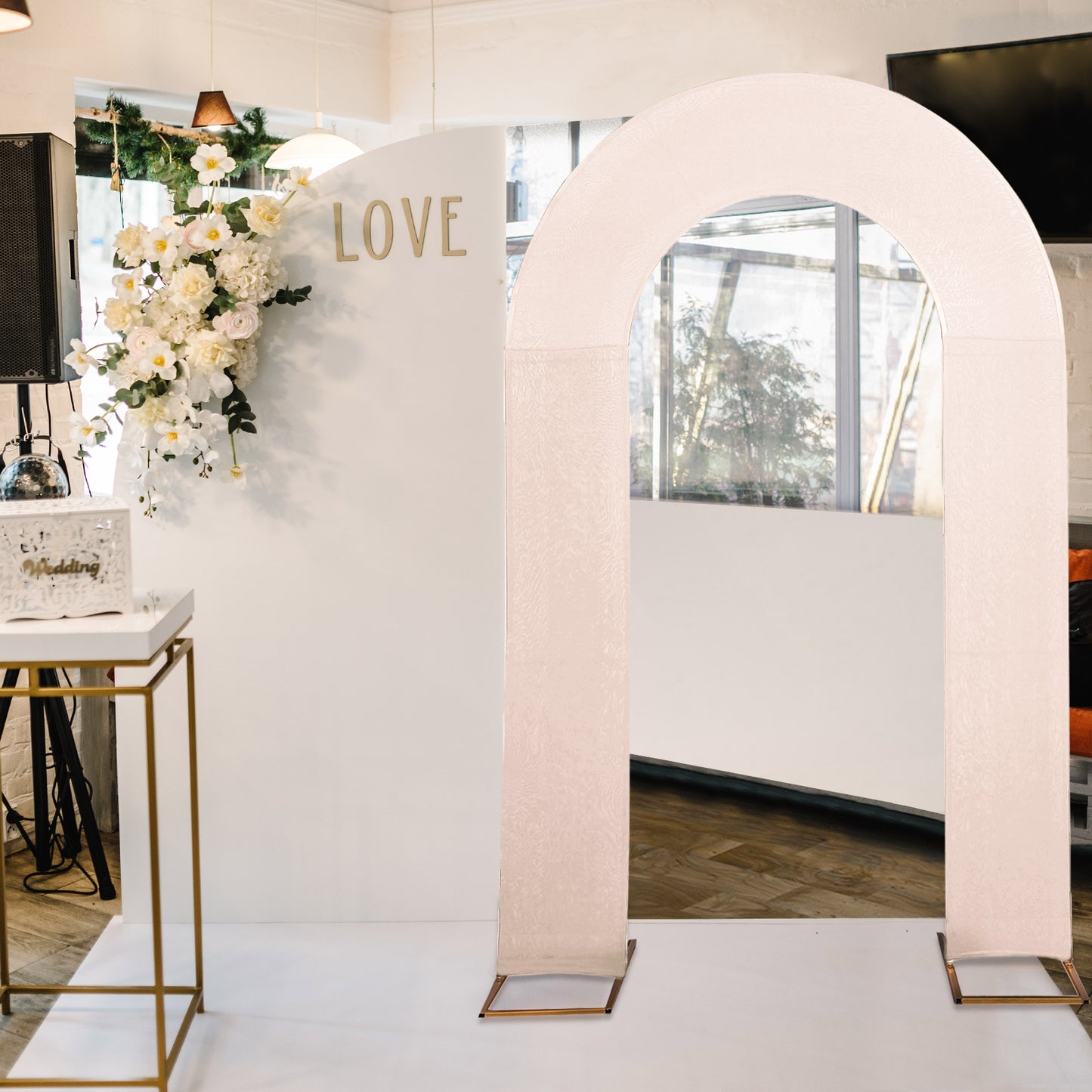 Blush spandex fitted wedding arch cover on display in elegant venue.