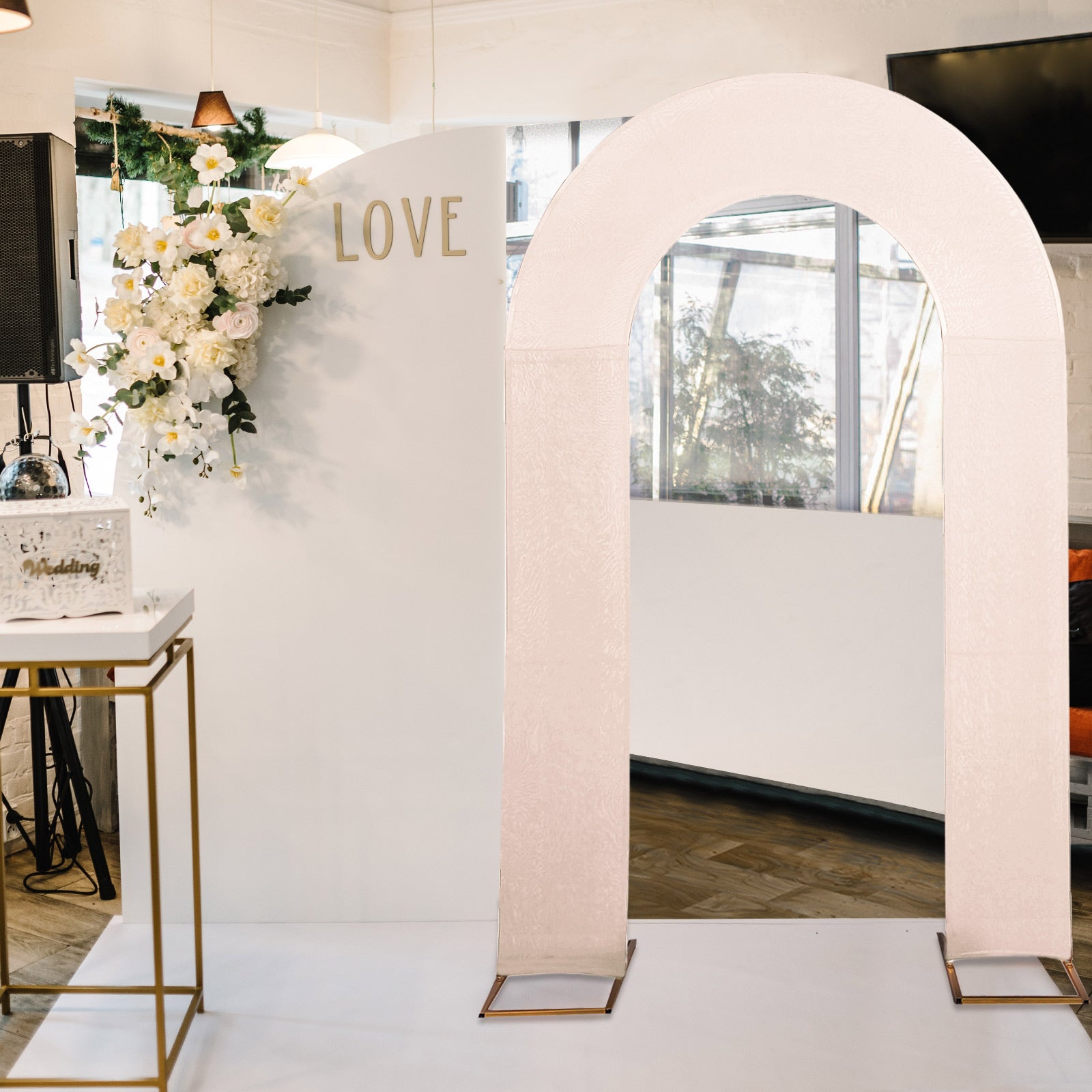 Blush spandex fitted wedding arch cover on display in elegant venue.