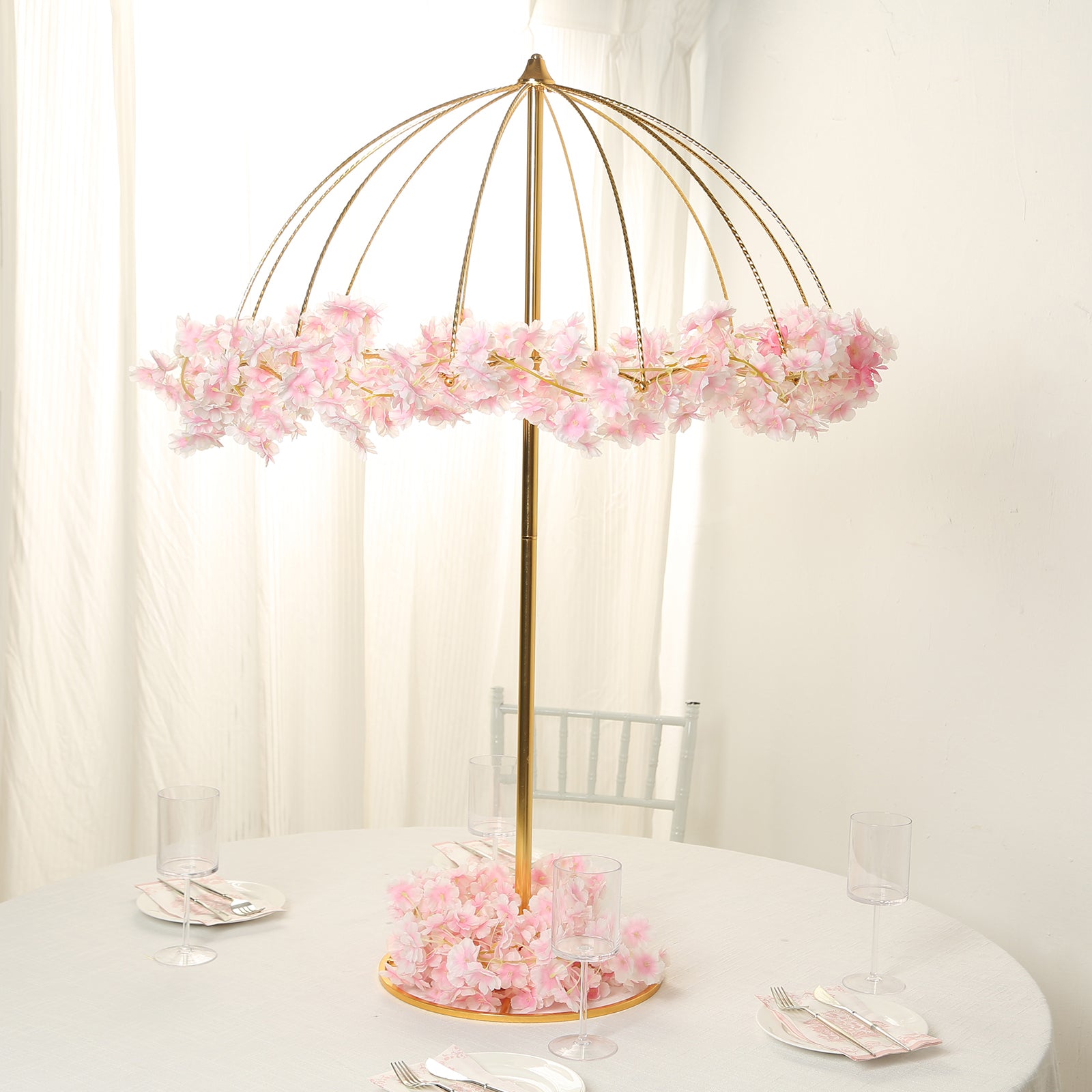 Gold floral umbrella stand with pink flowers, perfect for wedding centerpieces.