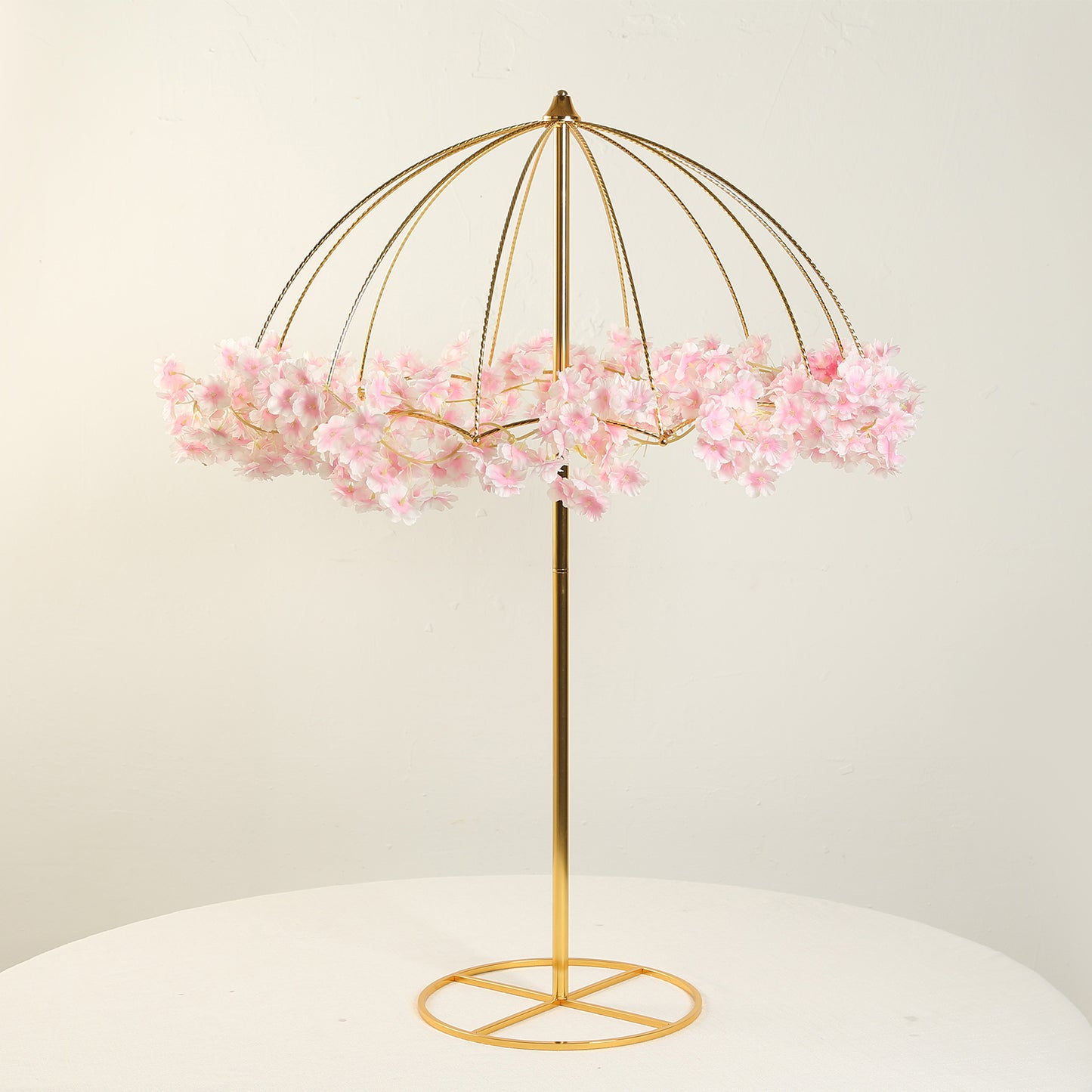 Gold metal umbrella flower stand with pink floral accents.