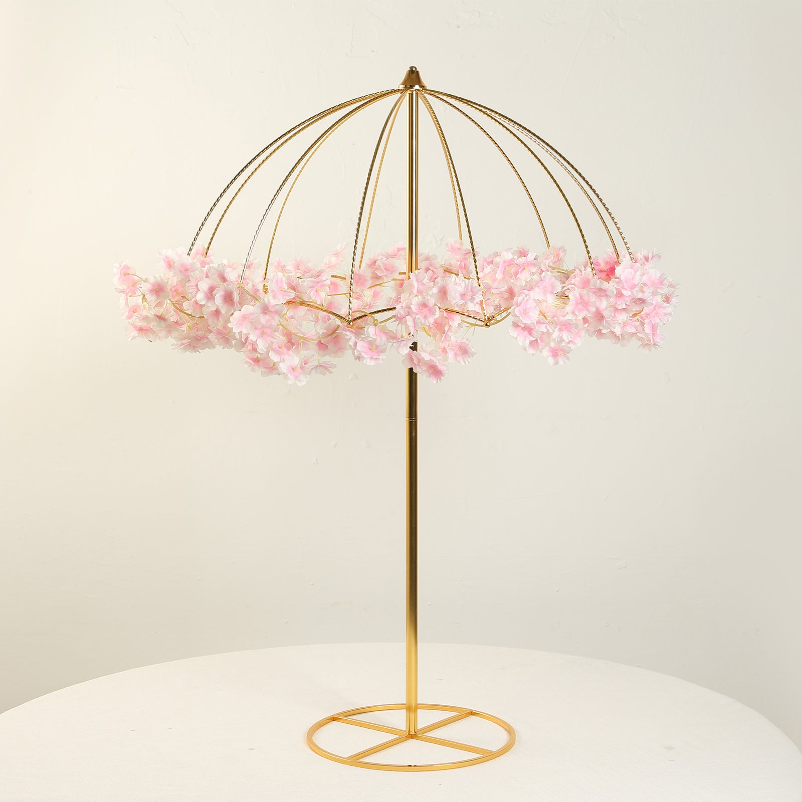 Gold metal umbrella flower stand with pink floral accents.
