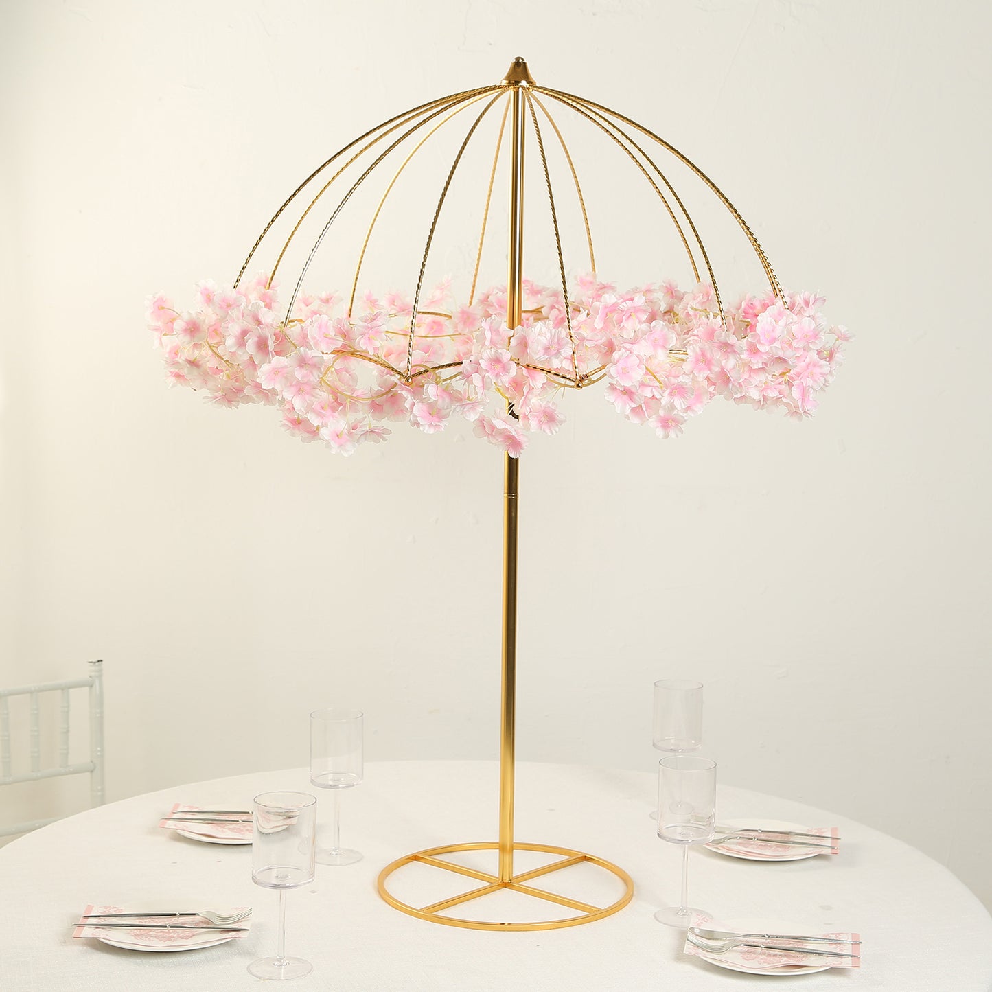 Gold metal umbrella flower stand with pink floral accents.