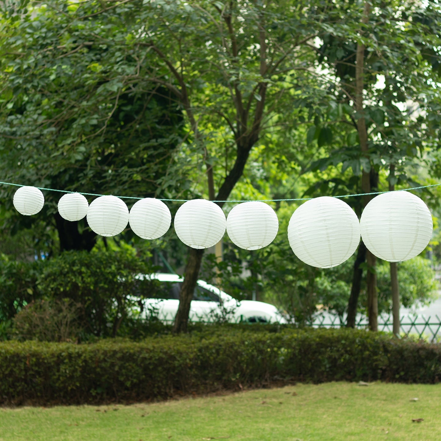 Set of 8 ivory hanging paper lanterns in assorted sizes.
