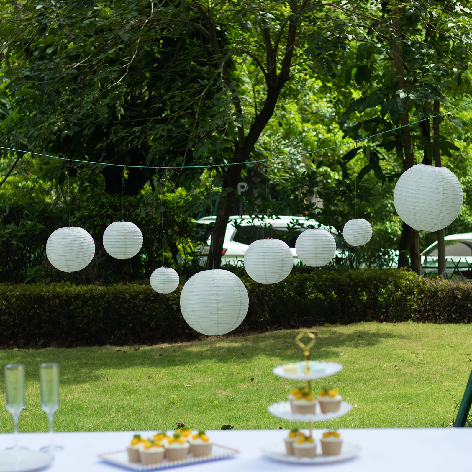 Set of 8 ivory hanging paper lanterns in assorted sizes.