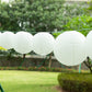 Set of 8 ivory hanging paper lanterns in assorted sizes.