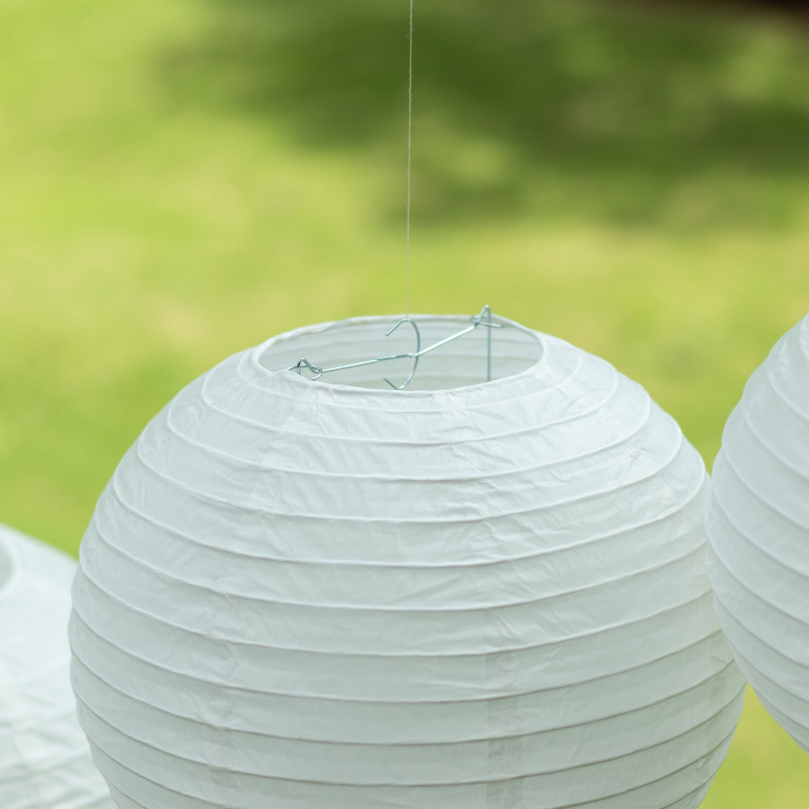 Ivory hanging paper lanterns in assorted sizes for decorative use.