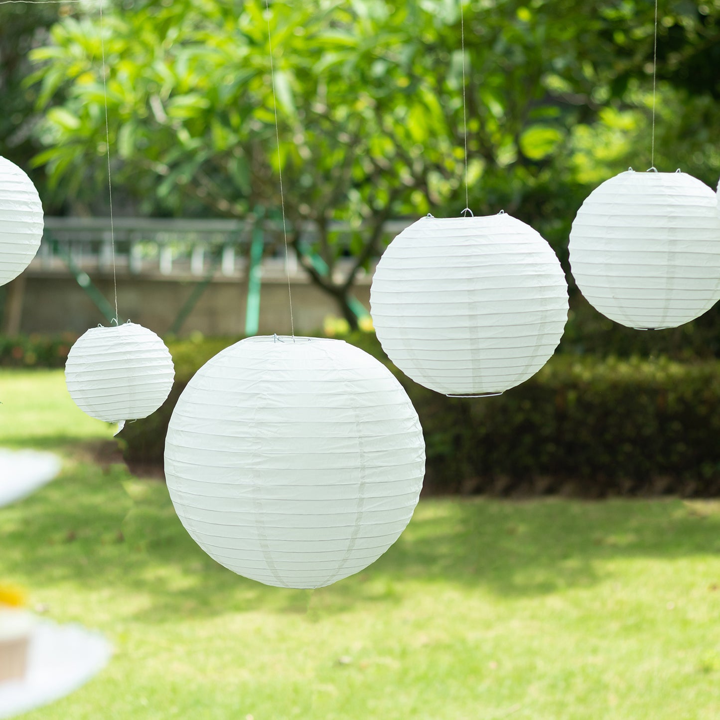 Set of 8 ivory hanging paper lanterns in assorted sizes.