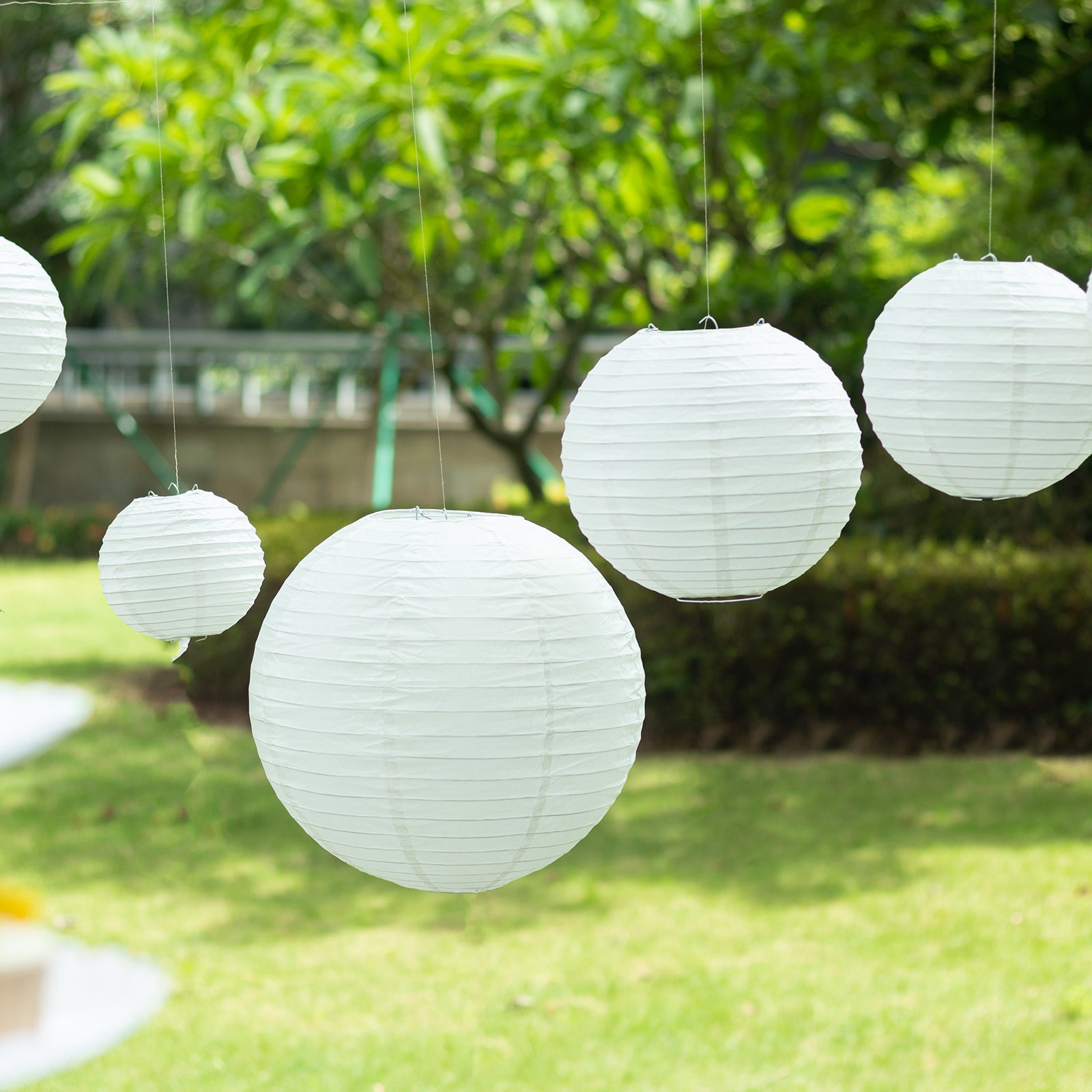 Set of 8 ivory hanging paper lanterns in assorted sizes.
