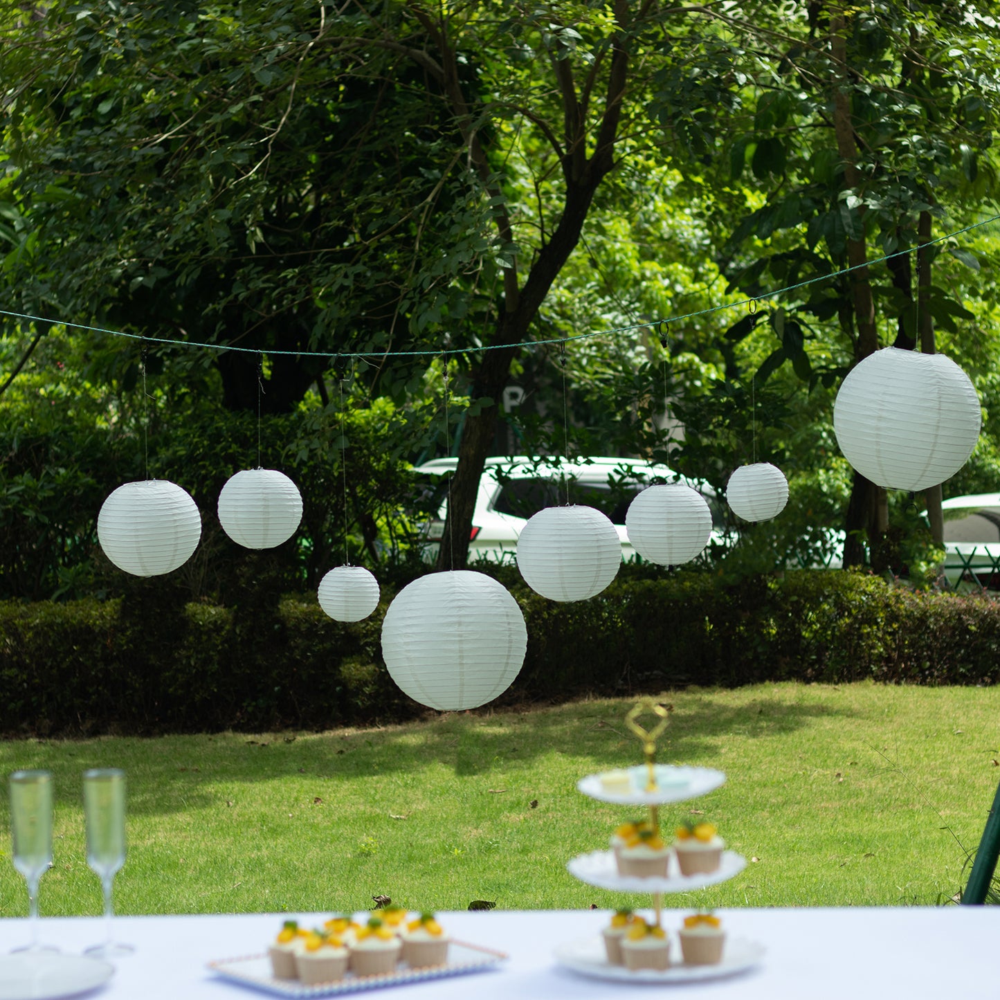 Set of 8 ivory hanging paper lanterns in assorted sizes.
