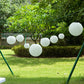 Ivory hanging paper lanterns in assorted sizes for outdoor decor.