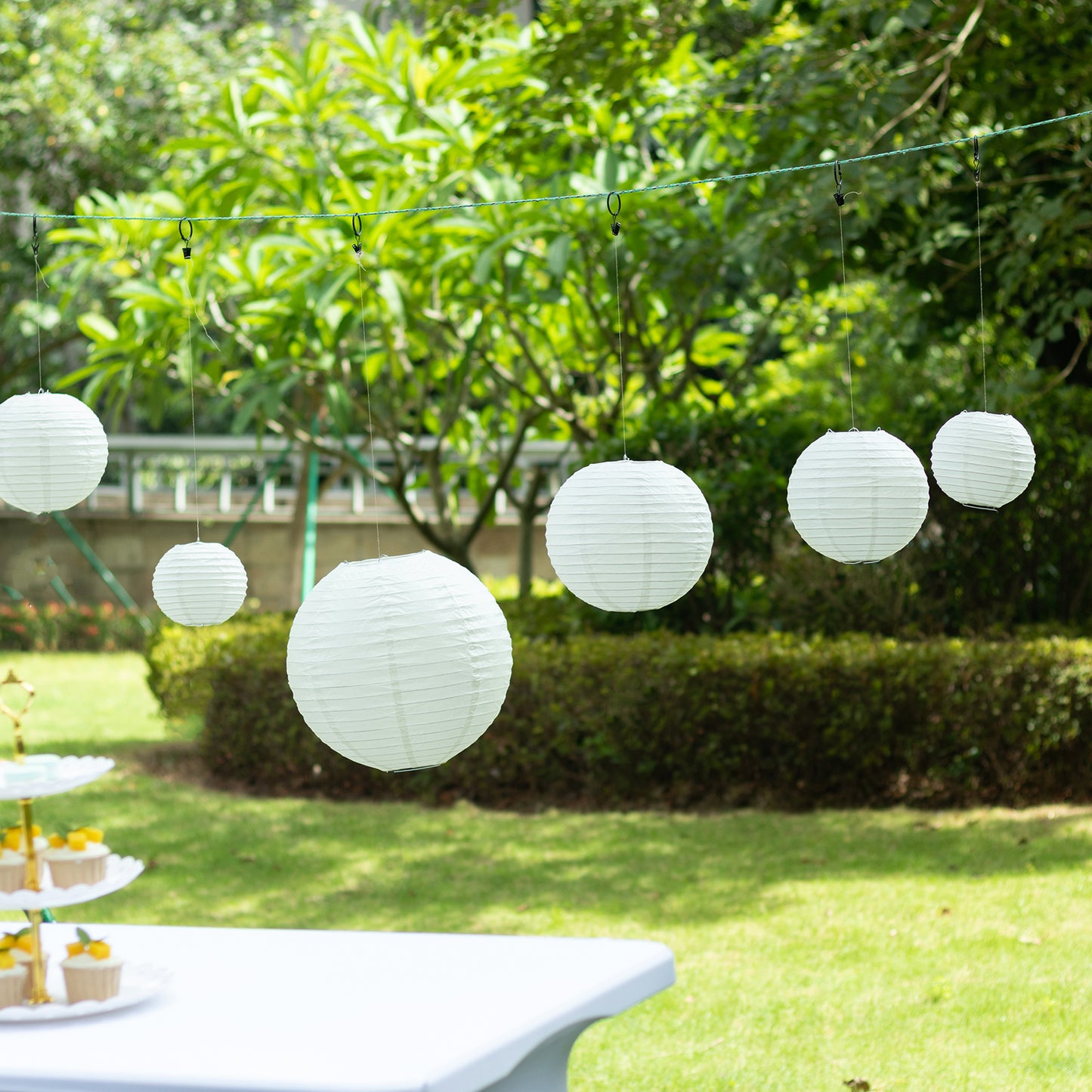 Set of 8 ivory hanging paper lanterns in assorted sizes.