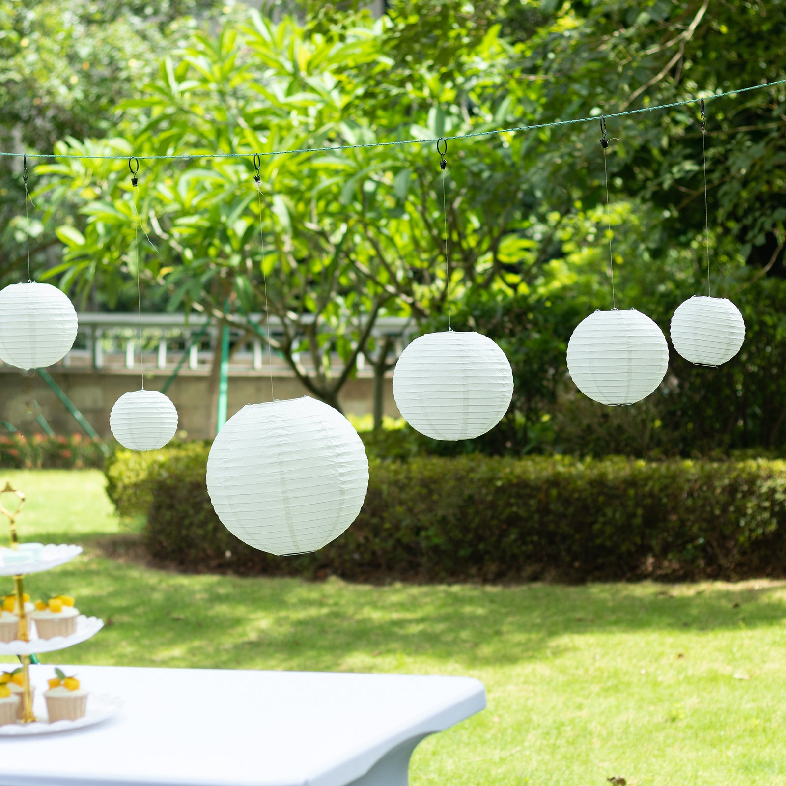 Set of 8 ivory hanging paper lanterns in assorted sizes.