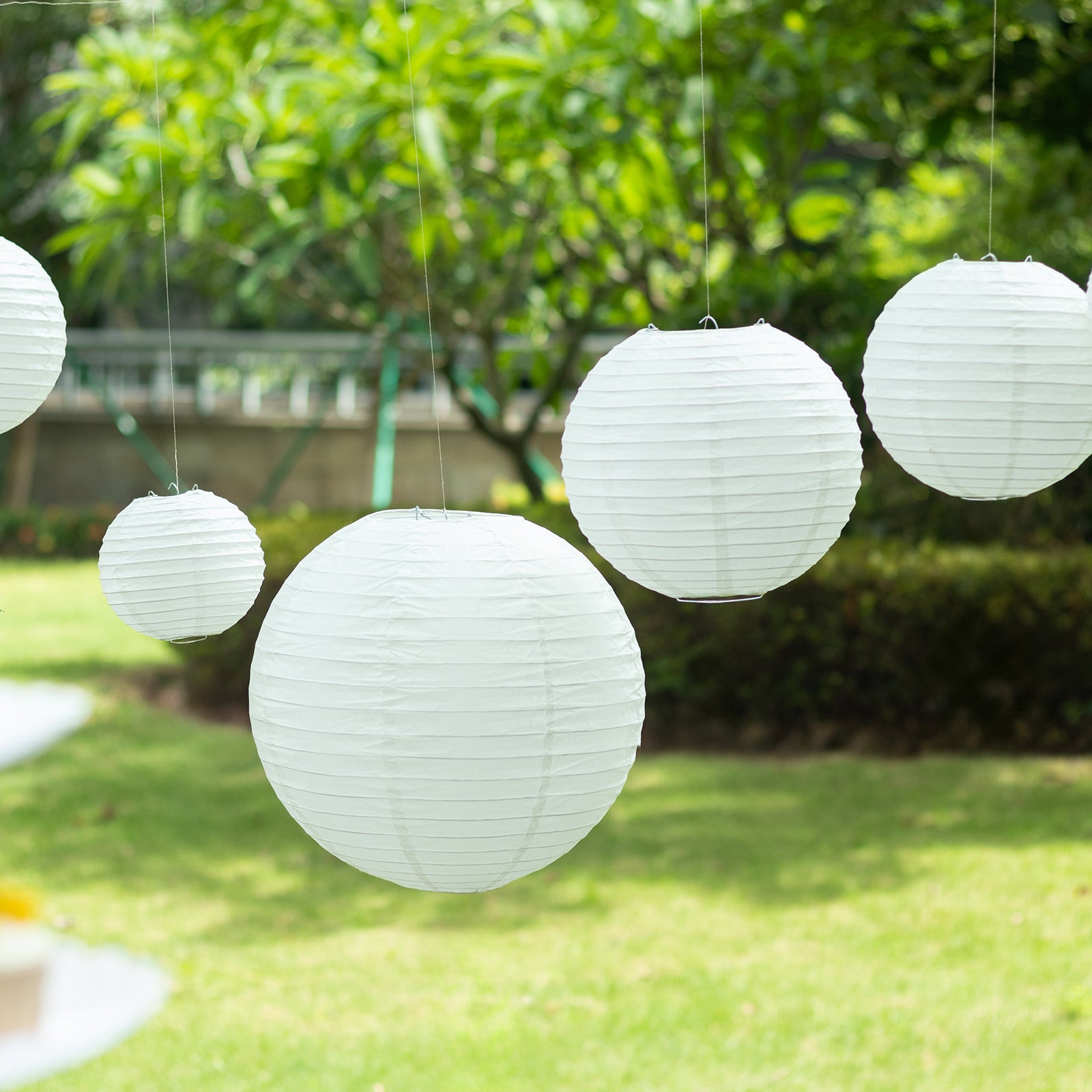 Set of 8 ivory hanging paper lanterns in assorted sizes.