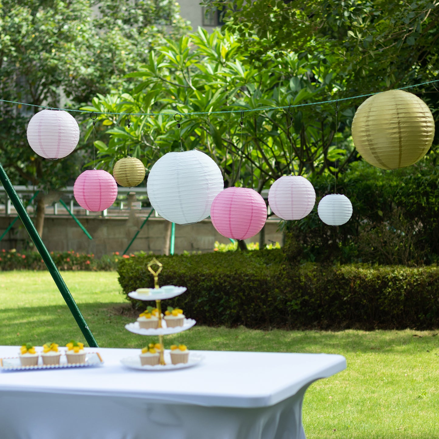 Set of 8 mixed blush gold hanging paper lanterns in assorted sizes.