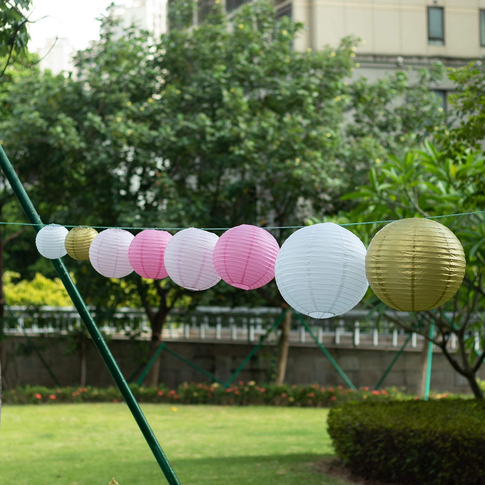 Set of 8 mixed blush gold hanging paper lanterns in assorted sizes.