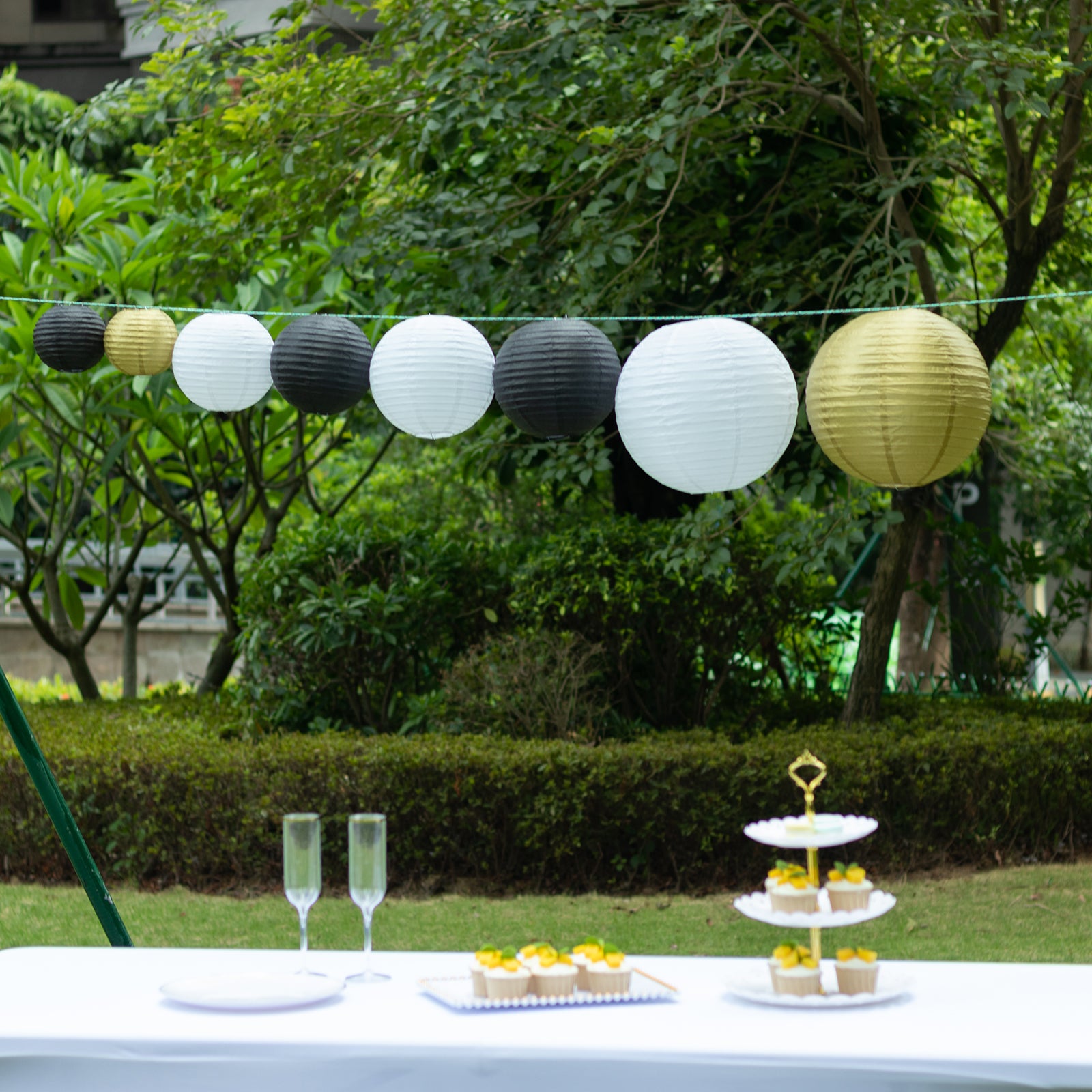 Set of 8 black and gold hanging paper lanterns in assorted sizes.