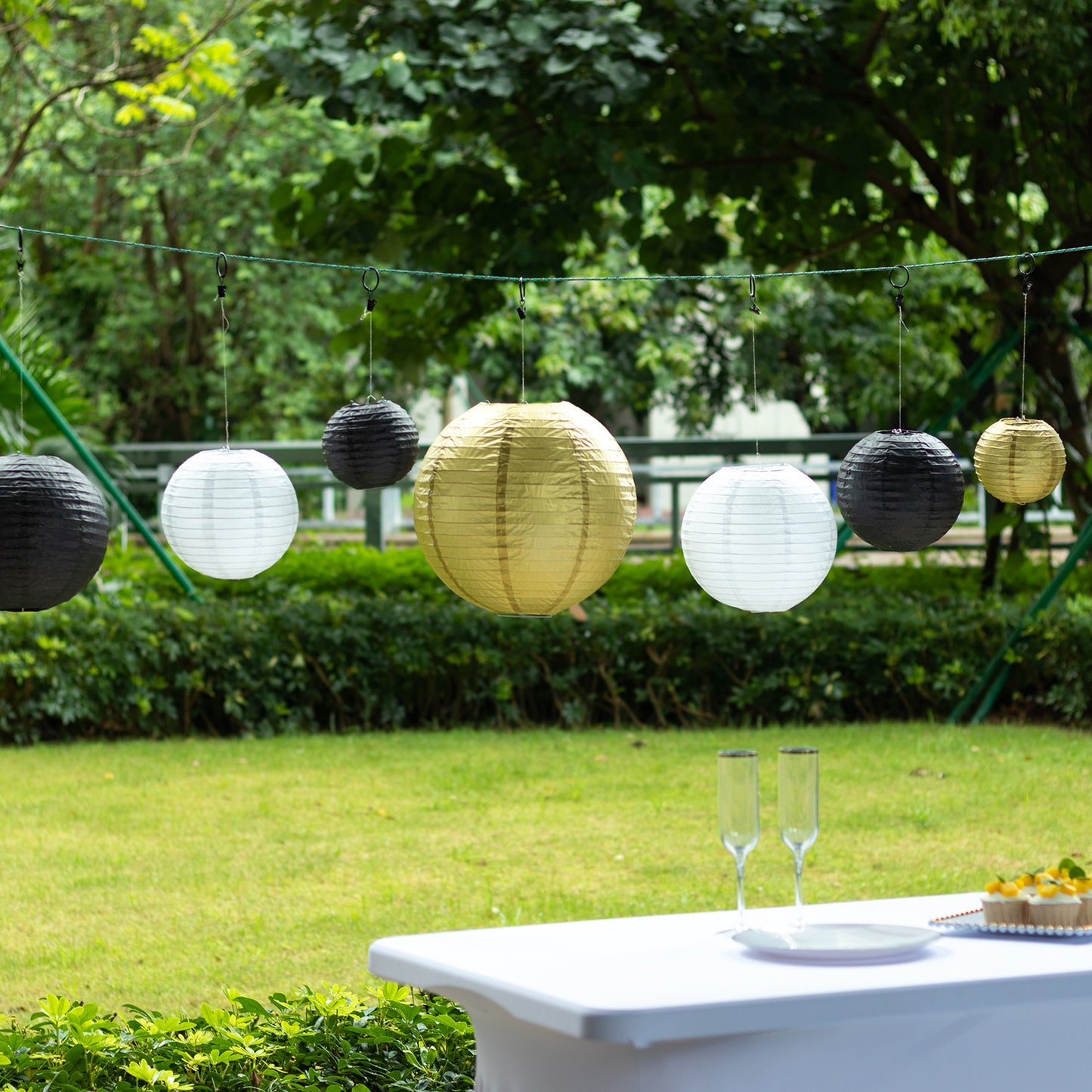Set of 8 black and gold hanging paper lanterns in assorted sizes.