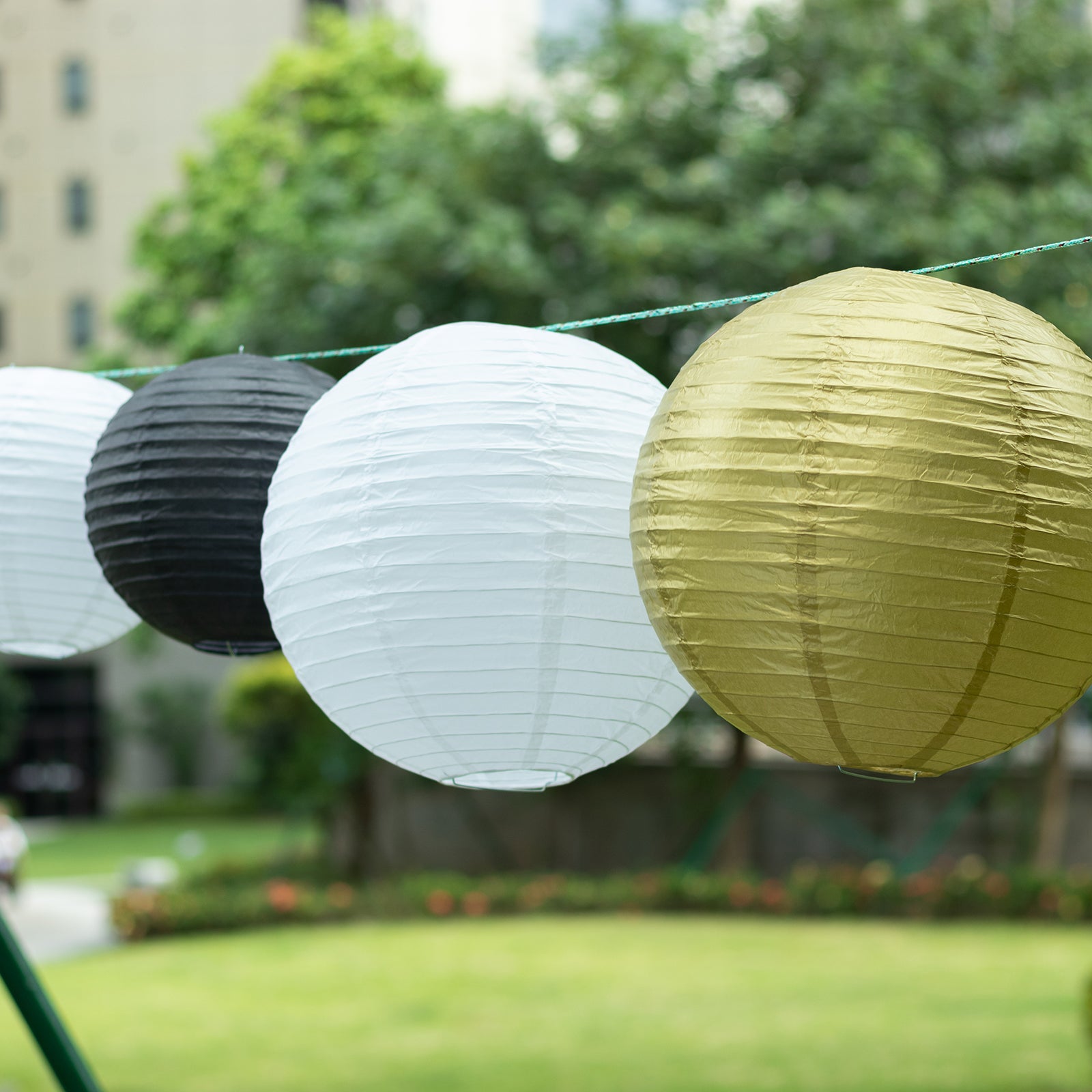 Set of 8 black and gold hanging paper lanterns in assorted sizes.