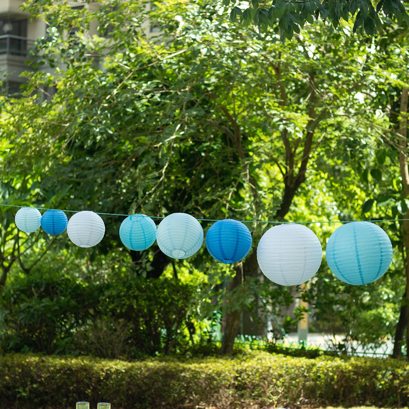 Set of 8 blue and white hanging paper lanterns in various sizes.