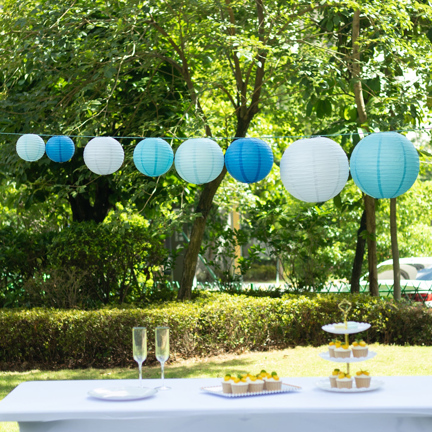 Set of 8 blue and white hanging paper lanterns in assorted sizes.