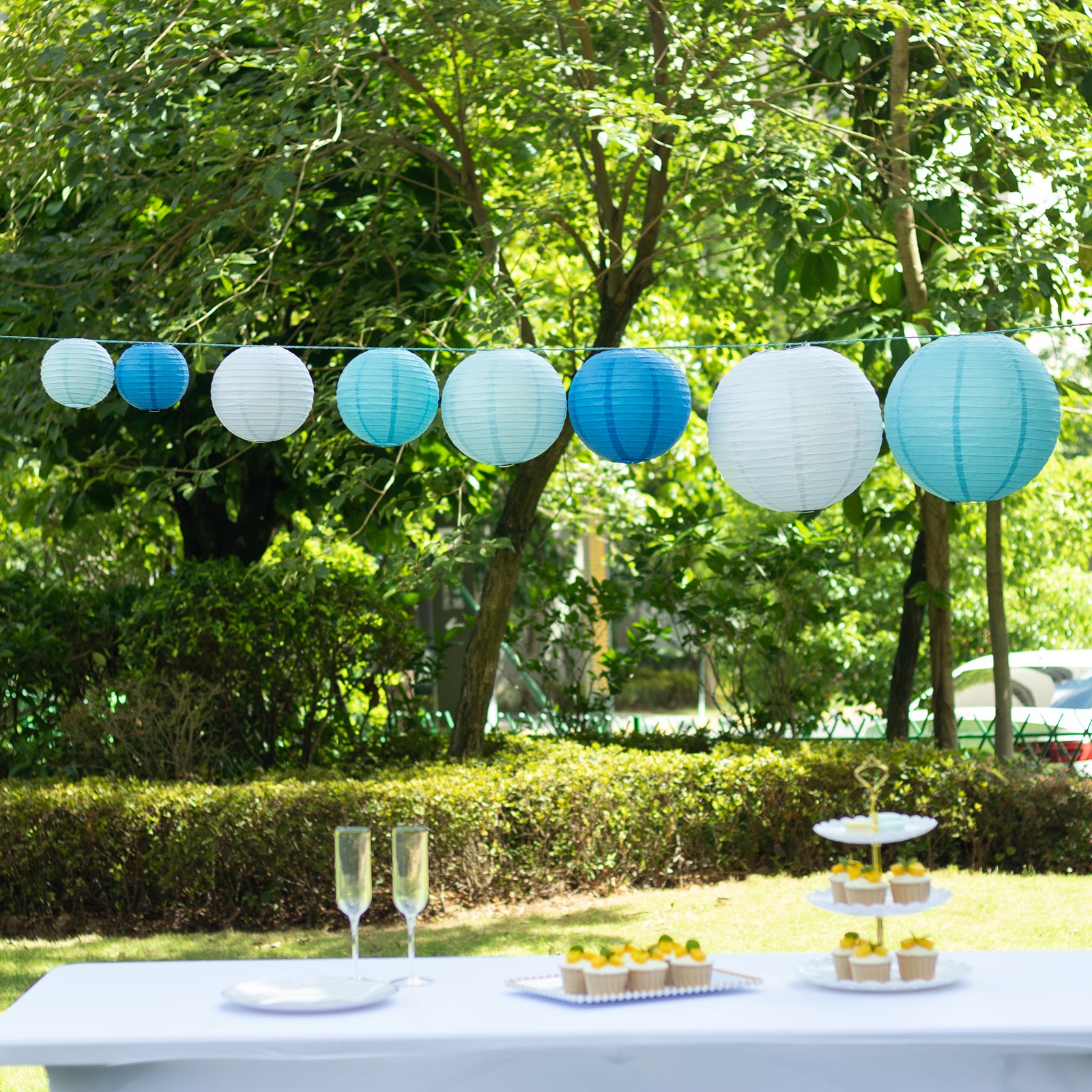 Set of 8 blue and white hanging paper lanterns in assorted sizes.