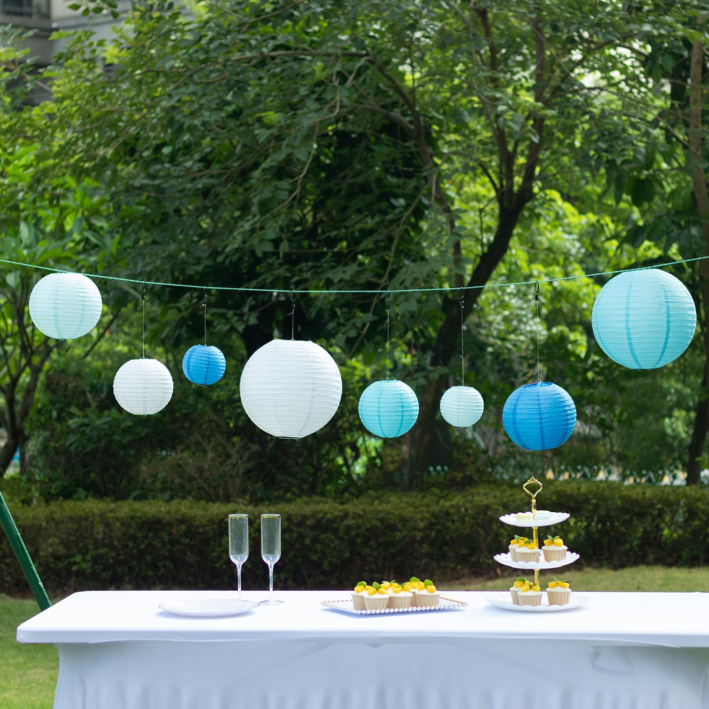 Set of 8 blue and white hanging paper lanterns in assorted sizes.