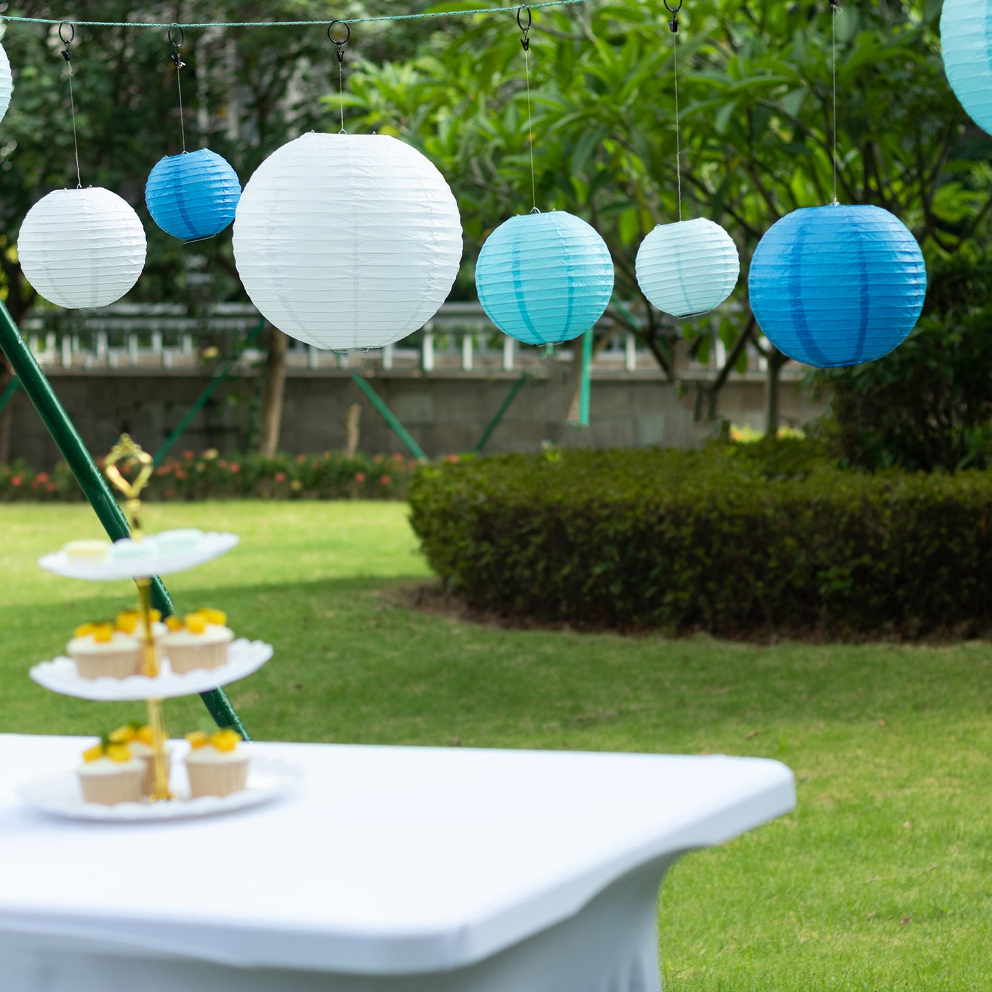 Set of 8 blue and white hanging paper lanterns in assorted sizes.