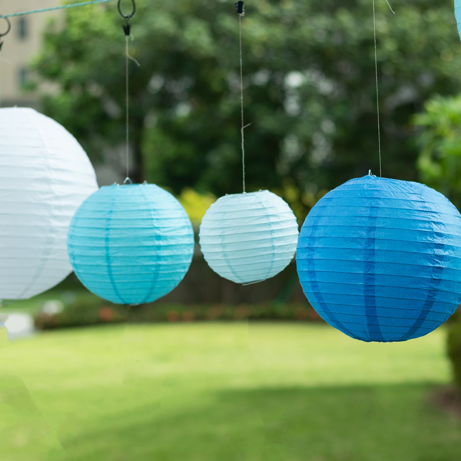 Set of 8 blue and white hanging paper lanterns in assorted sizes.
