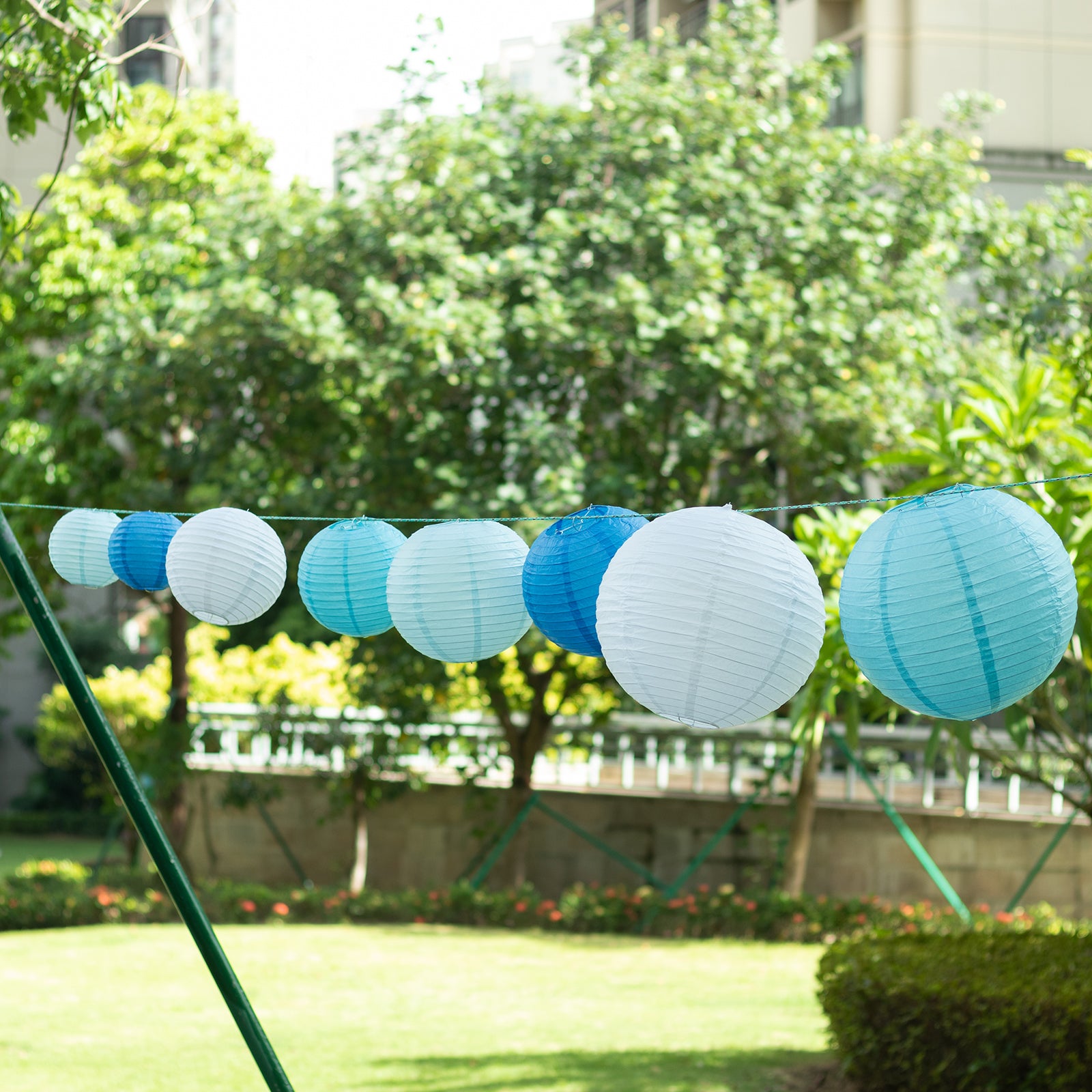 Set of 8 mixed blue and white hanging paper lanterns in assorted sizes.