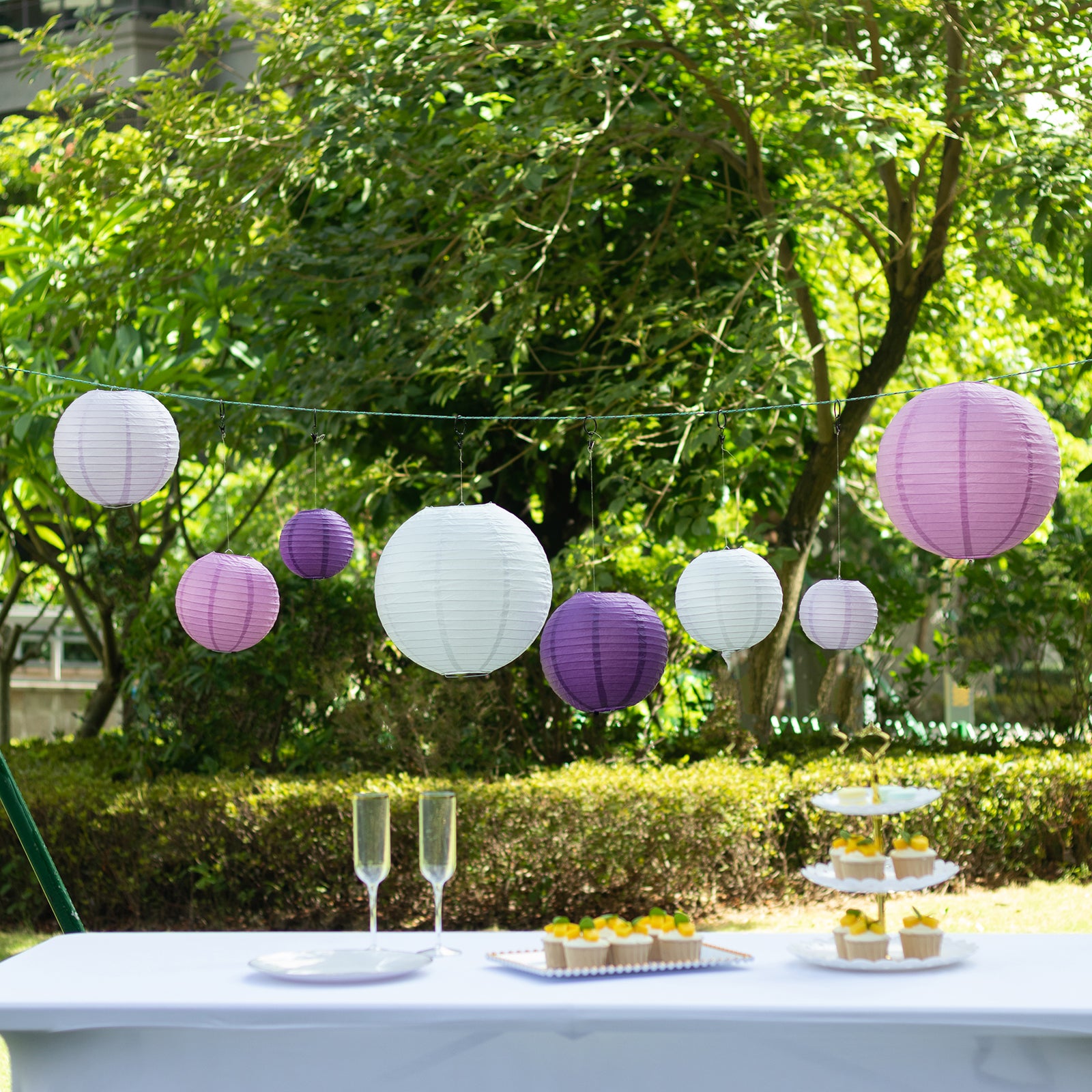 Set of 8 purple and white hanging paper lanterns in assorted sizes.