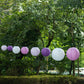 Set of 8 mixed purple and white hanging paper lanterns in assorted sizes.