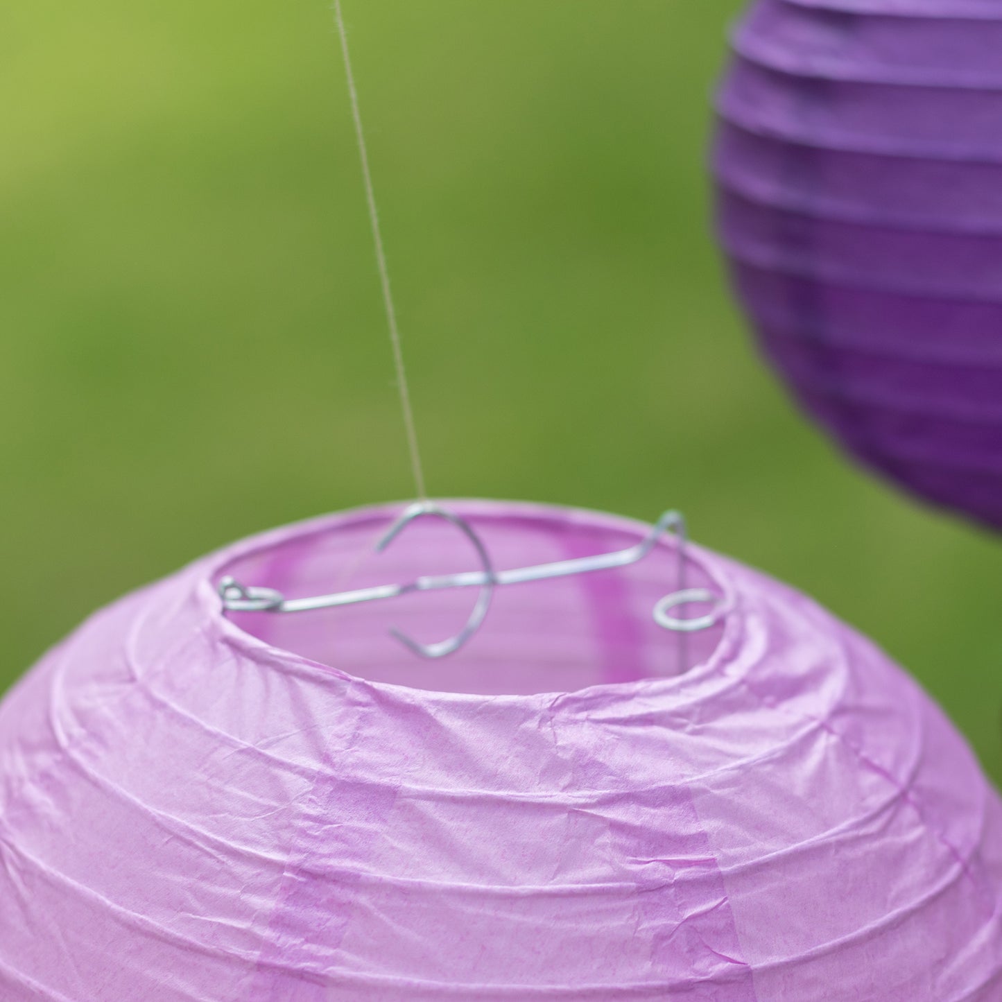Set of 8 purple and white hanging paper lanterns in assorted sizes.