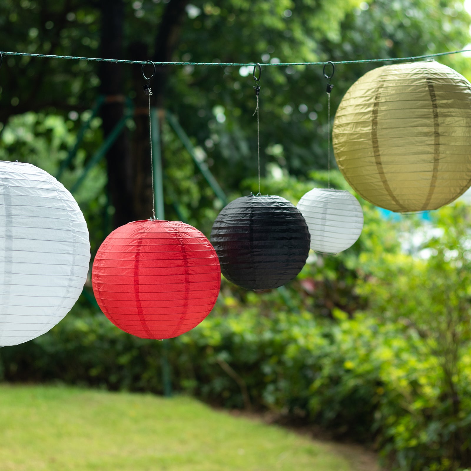 Set of 8 red and gold hanging paper lanterns in assorted sizes.