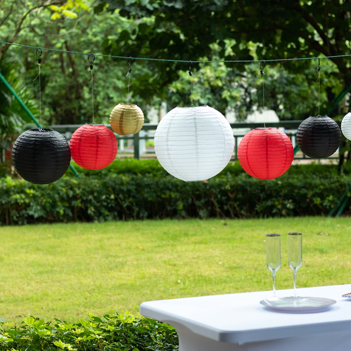 Set of 8 red and gold hanging paper lanterns in assorted sizes.