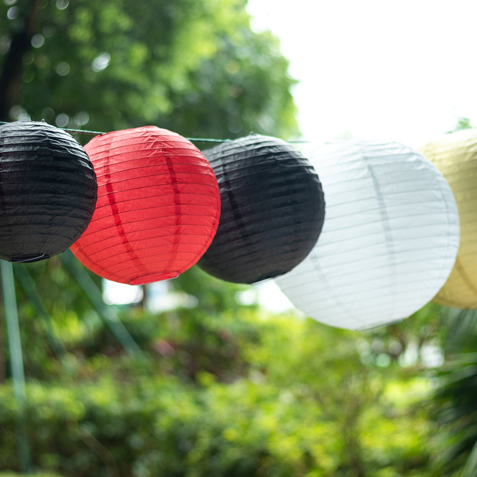 Set of 8 red and gold hanging paper lanterns in assorted sizes.